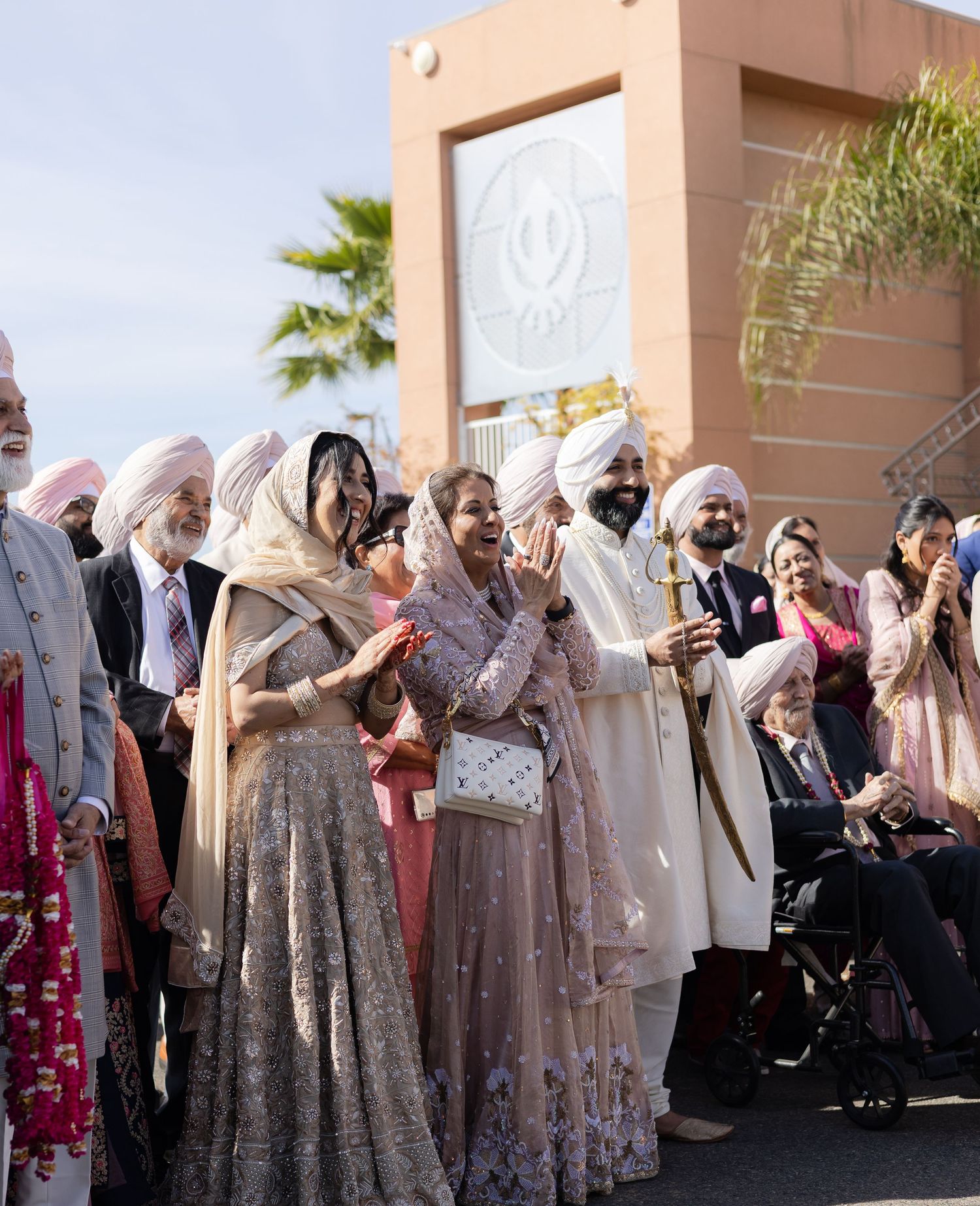 Wedding guests in traditional Indian attire gathered outside a building during a celebration.