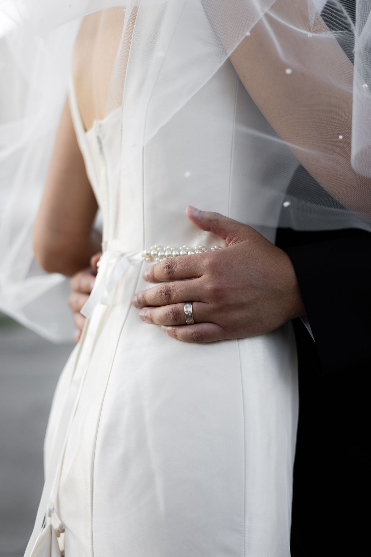 Close-up details of a bride's white wedding dress with delicate beading and elegant tailoring.
