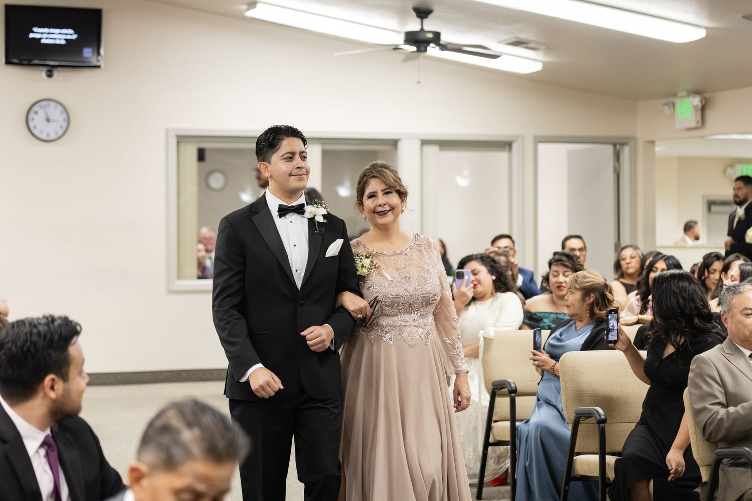 People gathered in a reception hall with fluorescent lighting and carpeted floors.