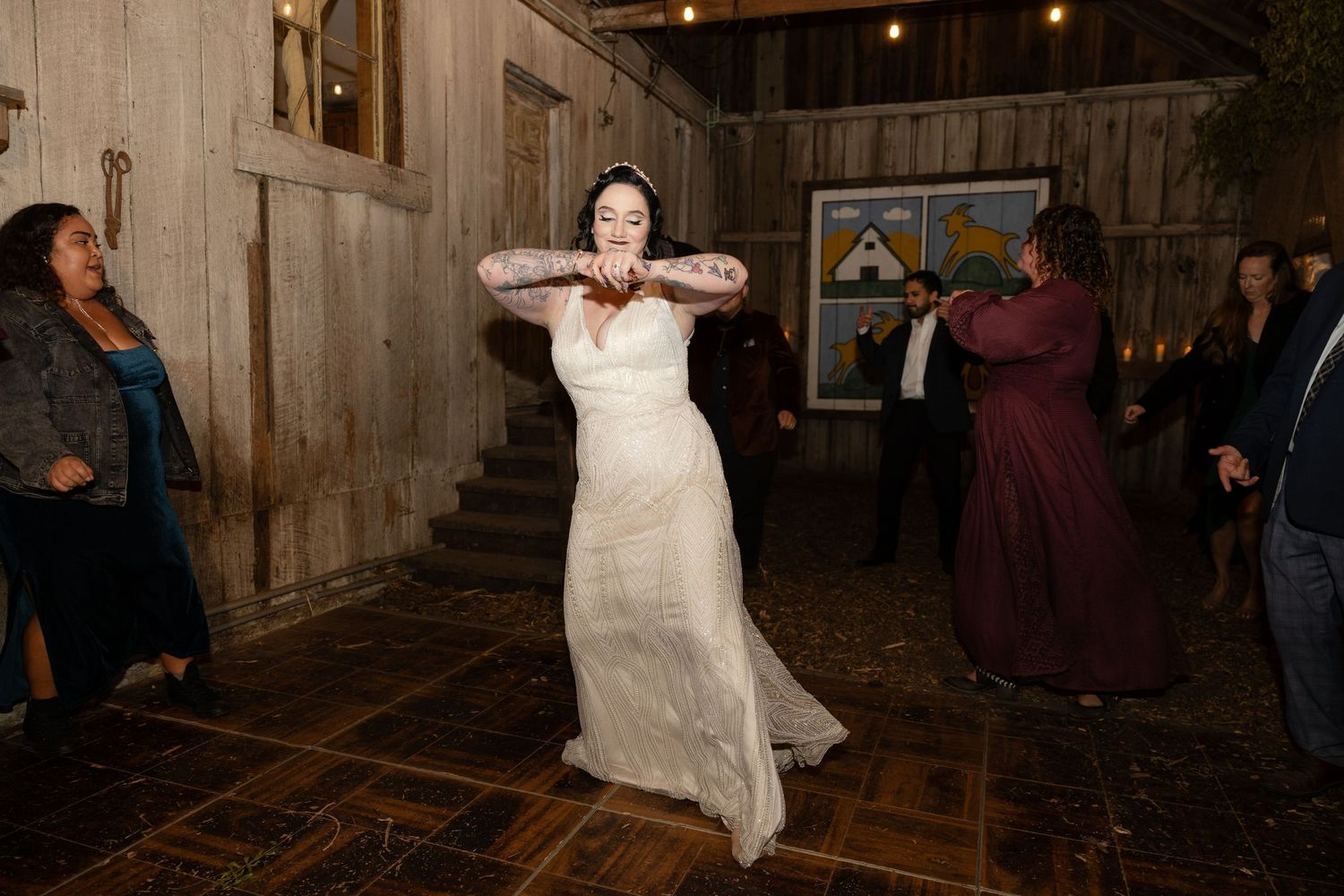 Lively dancing at a rustic barn wedding reception with wooden walls and mood lighting.