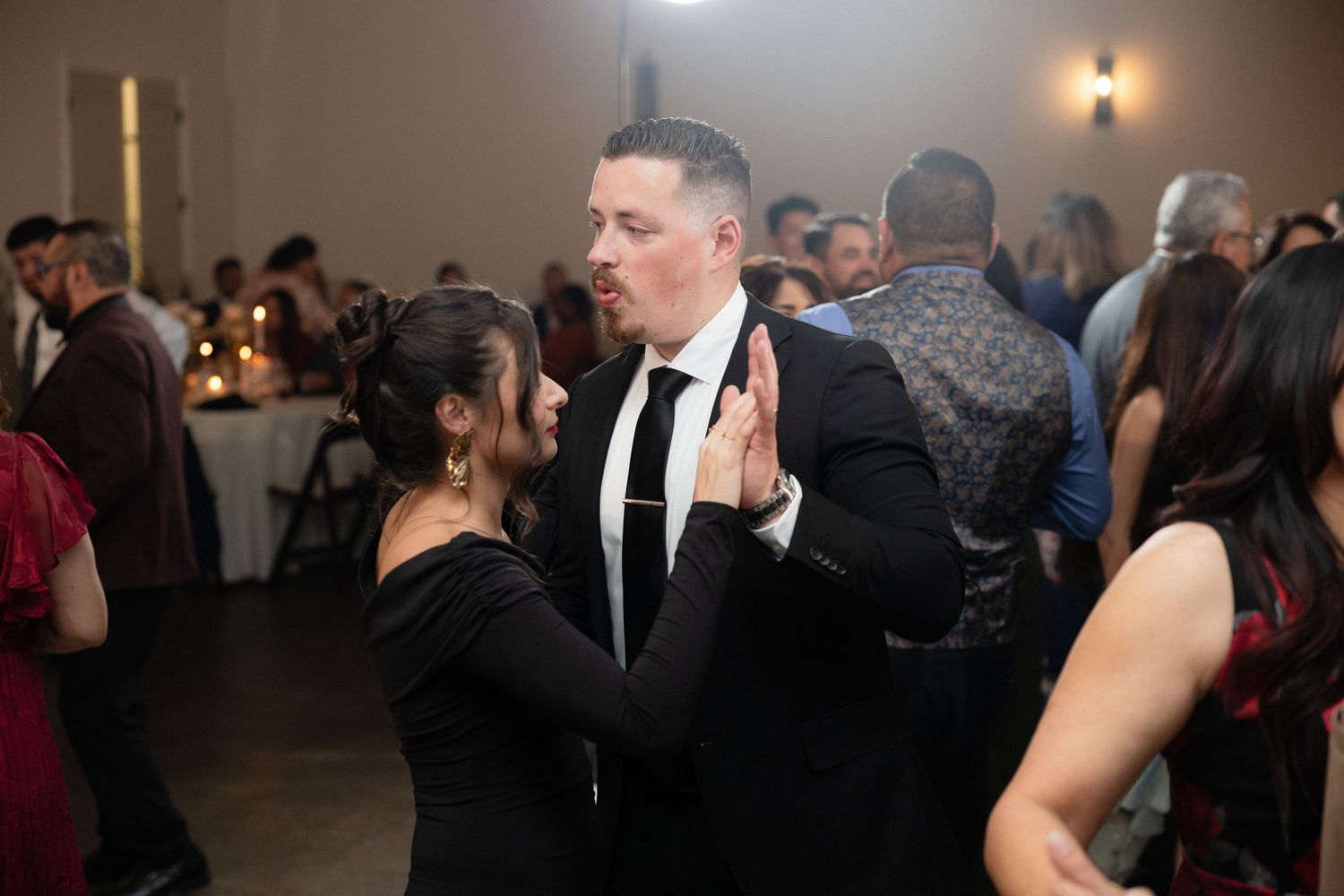 Couple dancing closely together at lively wedding reception celebration.