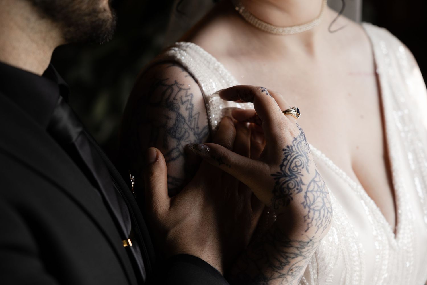 Close-up of tattooed hands holding during intimate wedding moment.