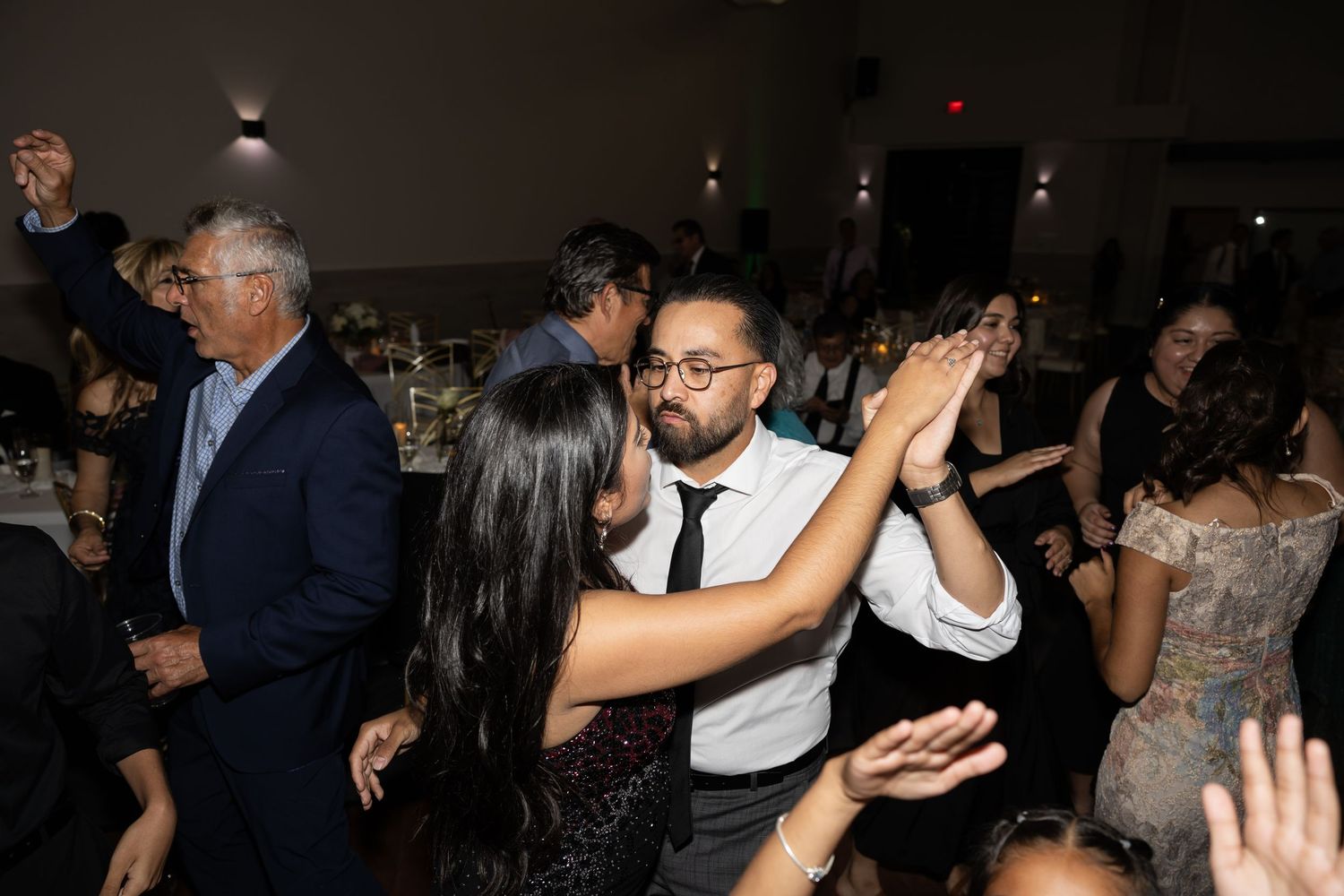 Crowded dance floor at a wedding reception with guests celebrating in formal attire.
