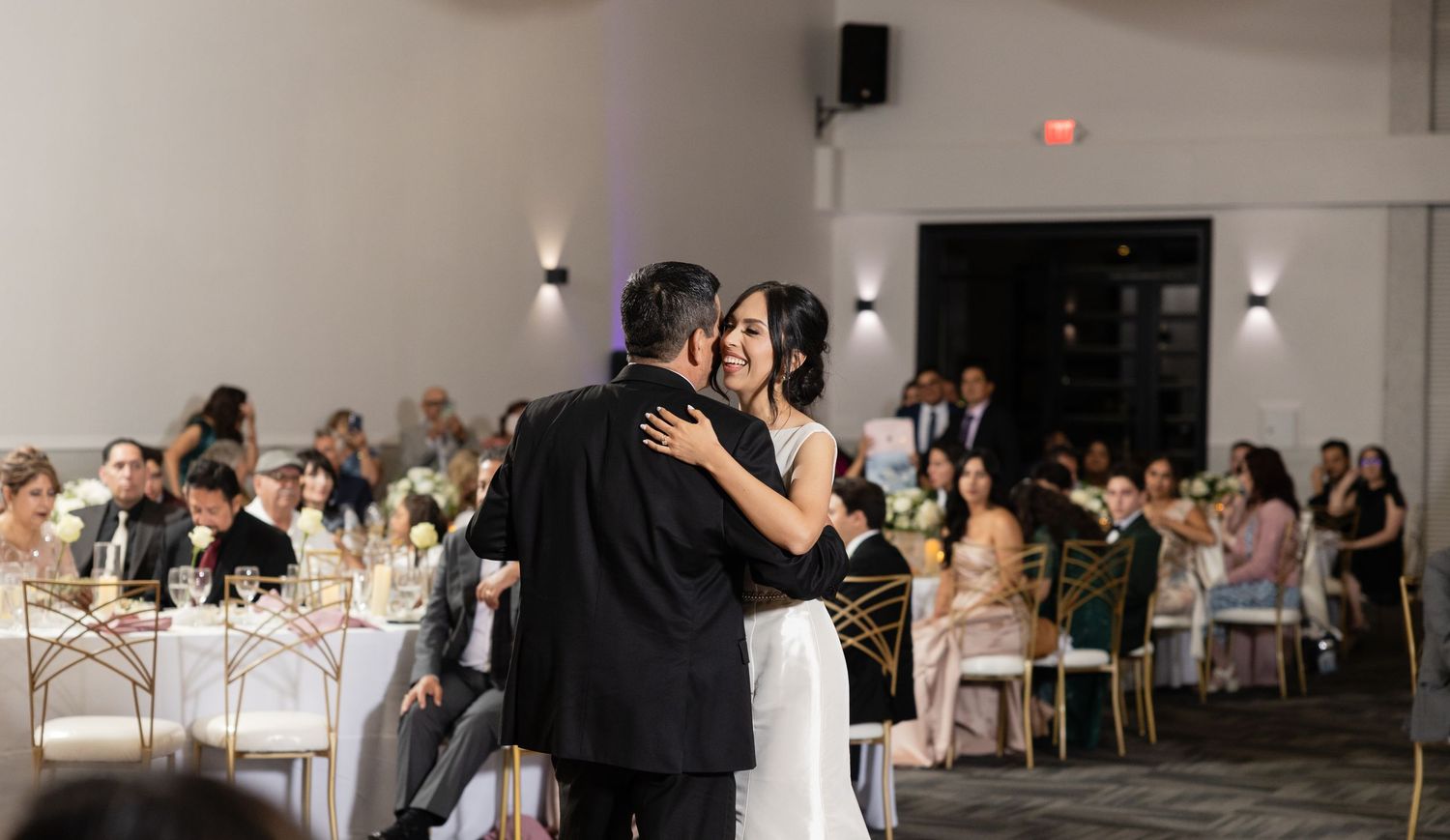Wedding reception venue with white draping and elegant table settings.