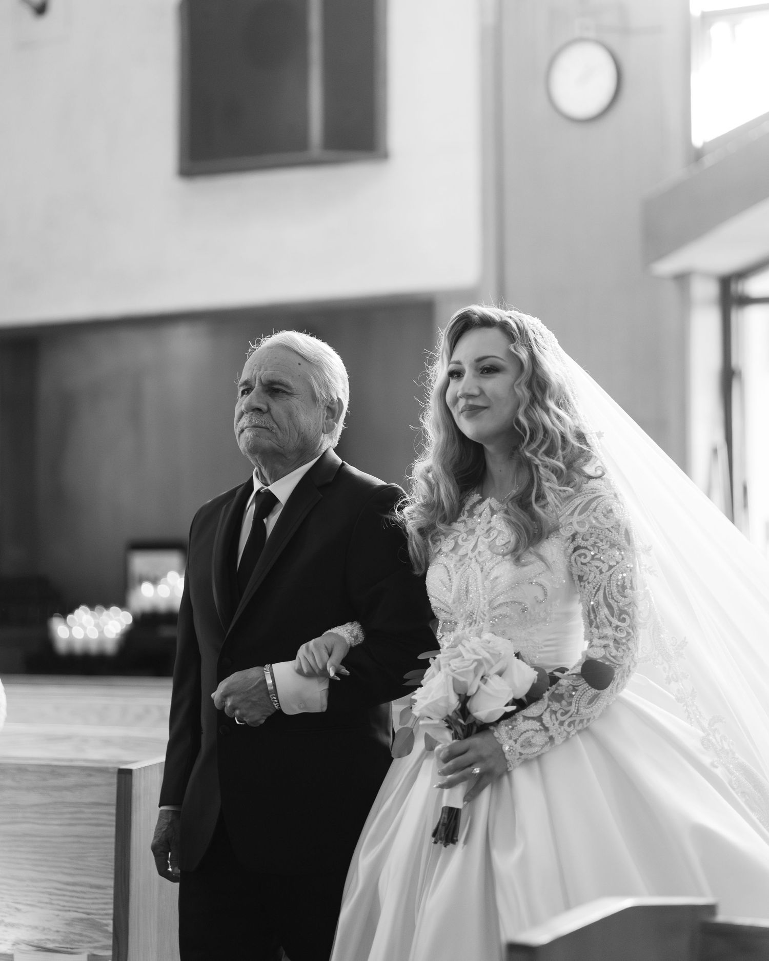 Wedding ceremony in progress with bride in white lace dress walking down church aisle.