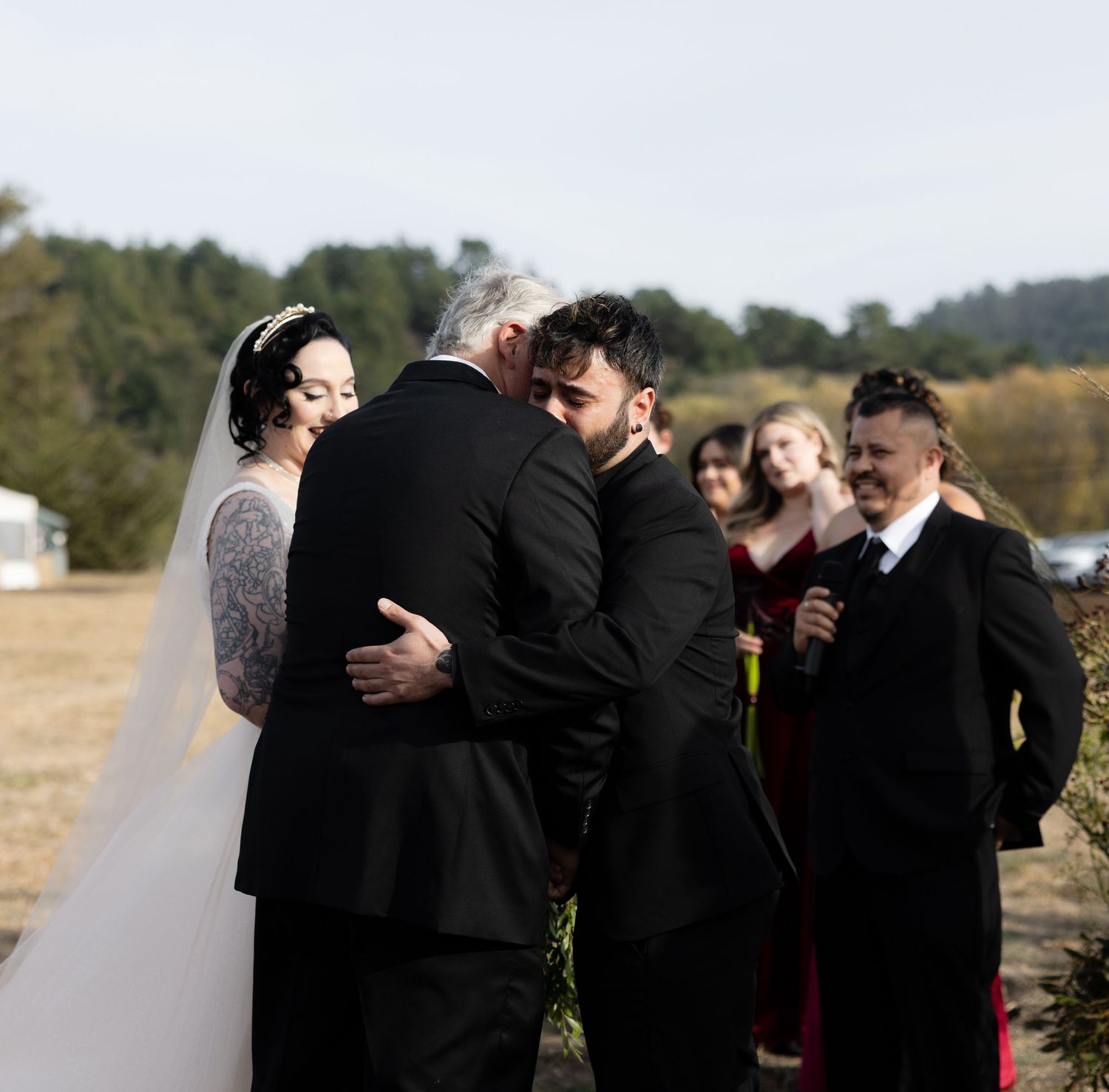 Wedding guests embrace and celebrate during an emotional outdoor ceremony moment.