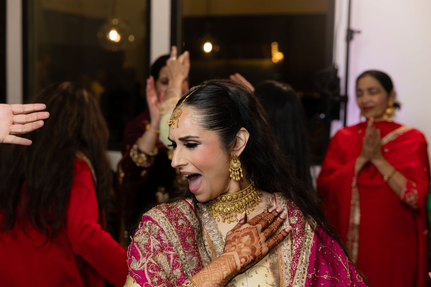 Wedding celebration with guests in red outfits dancing and celebrating in an indoor venue.