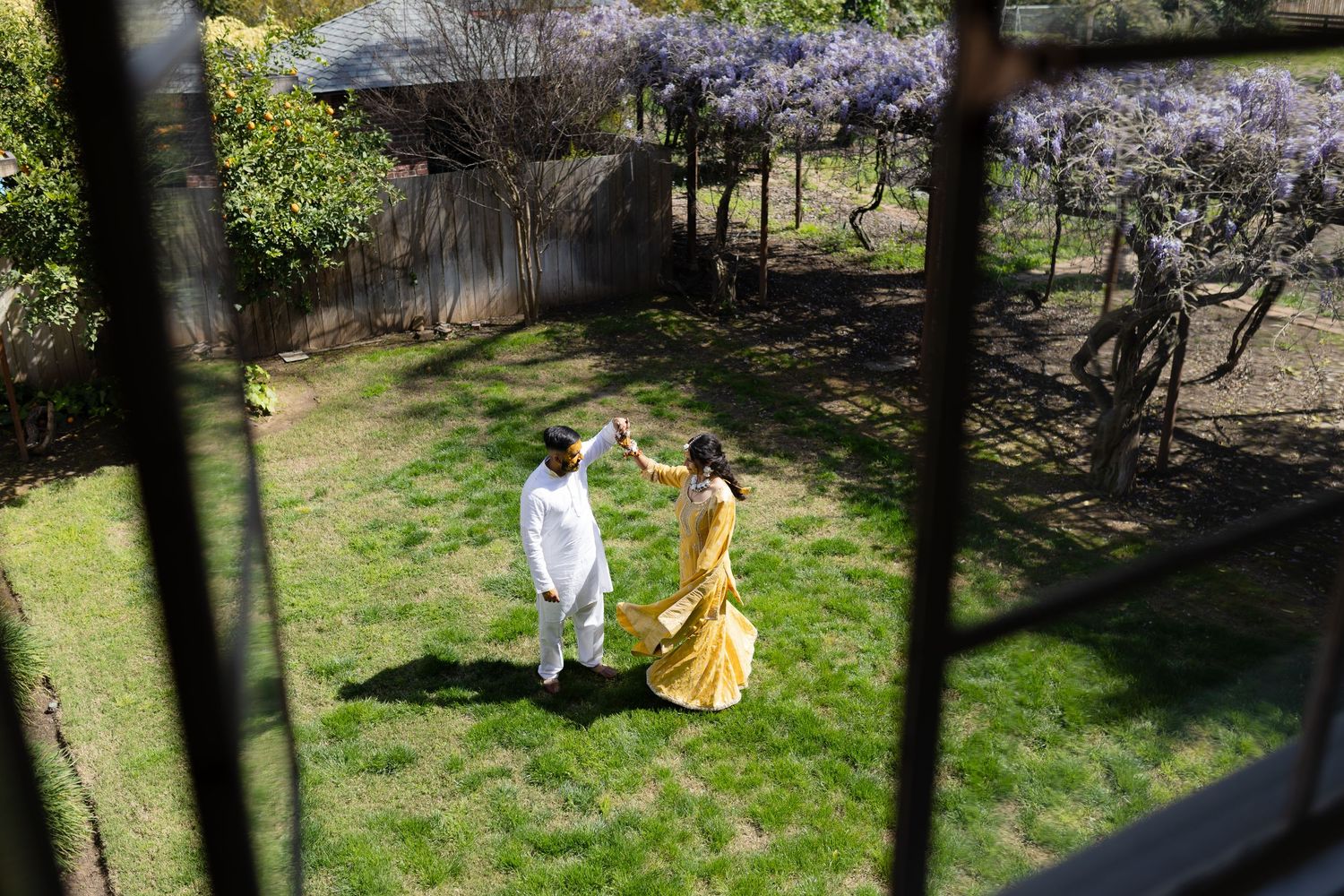 Two people in flowing dresses dance gracefully in a blooming spring garden with cherry blossoms.