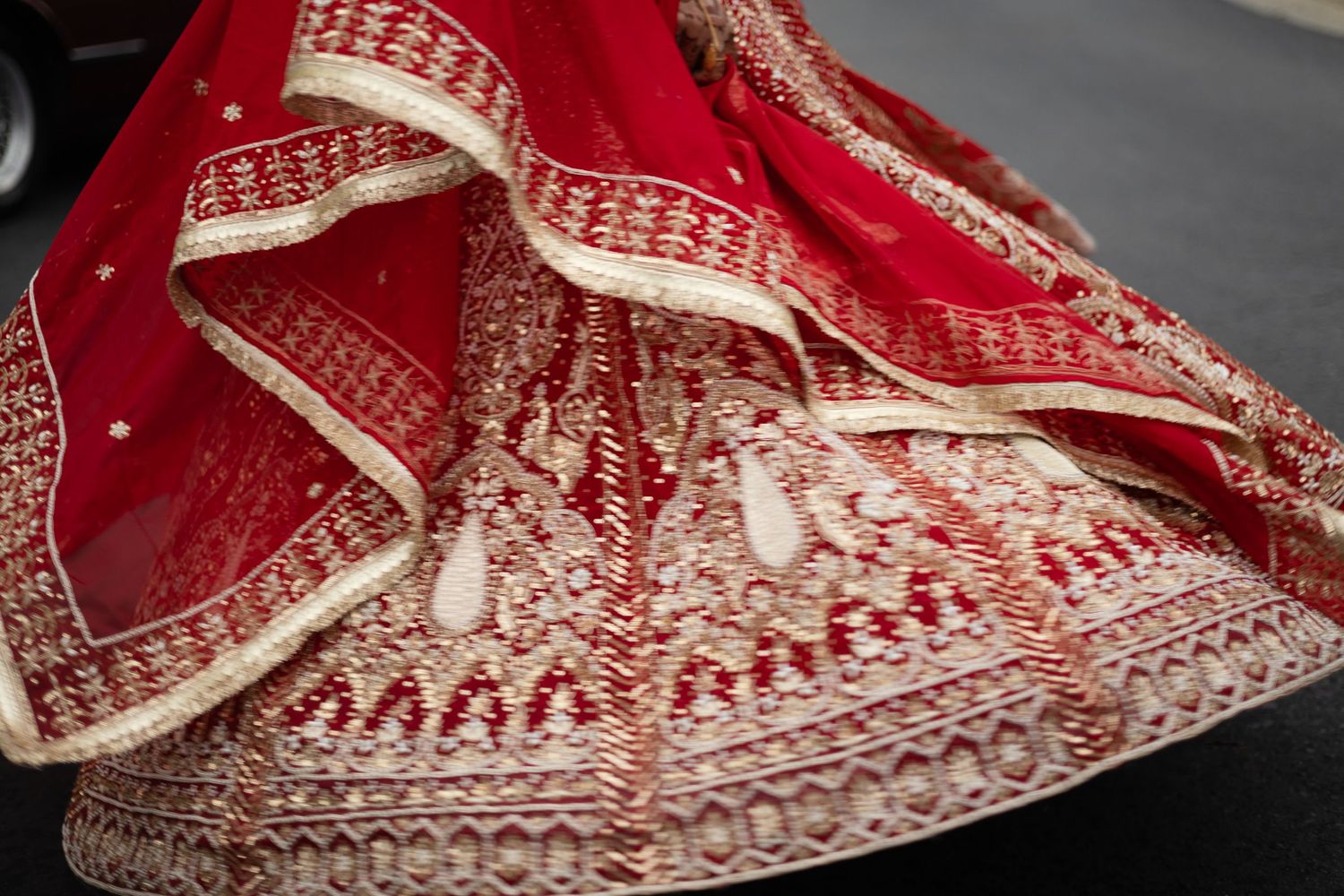 Close-up detail of an ornate red and gold embroidered Indian wedding lehenga or sari.