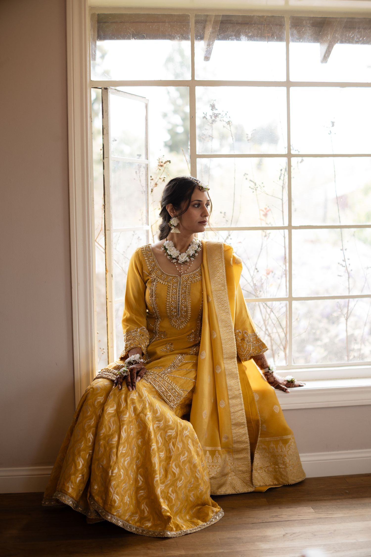 Elegant yellow embroidered dress with intricate details shown in multiple poses by a bright window.
