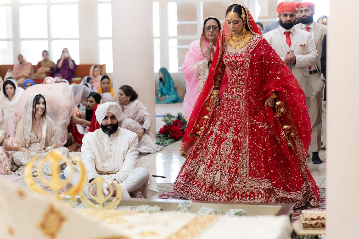Traditional Sikh wedding ceremony with bride in red lehenga and guests seated during religious rituals at the gurdwara.