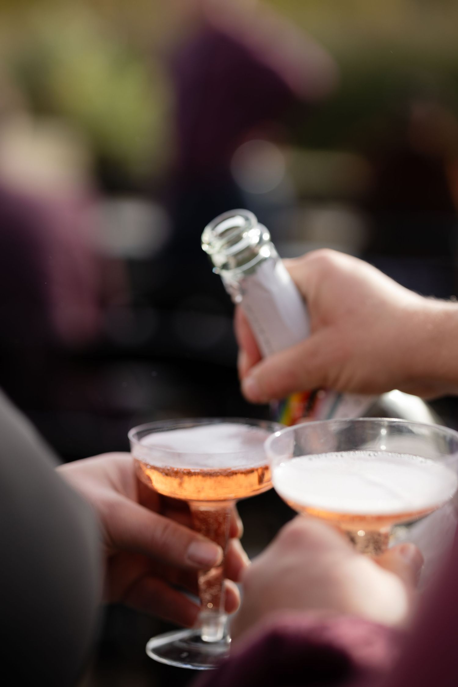 Close-up of champagne glasses being toasted at an outdoor celebration.