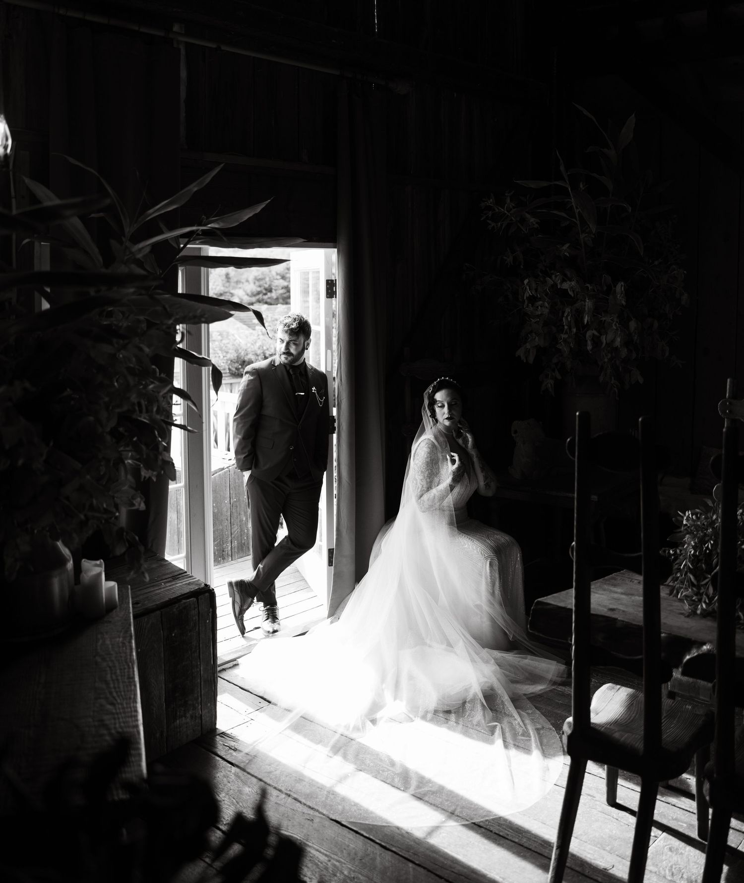 Wedding dress silhouette framed in doorway with dramatic contrast between light and shadow.