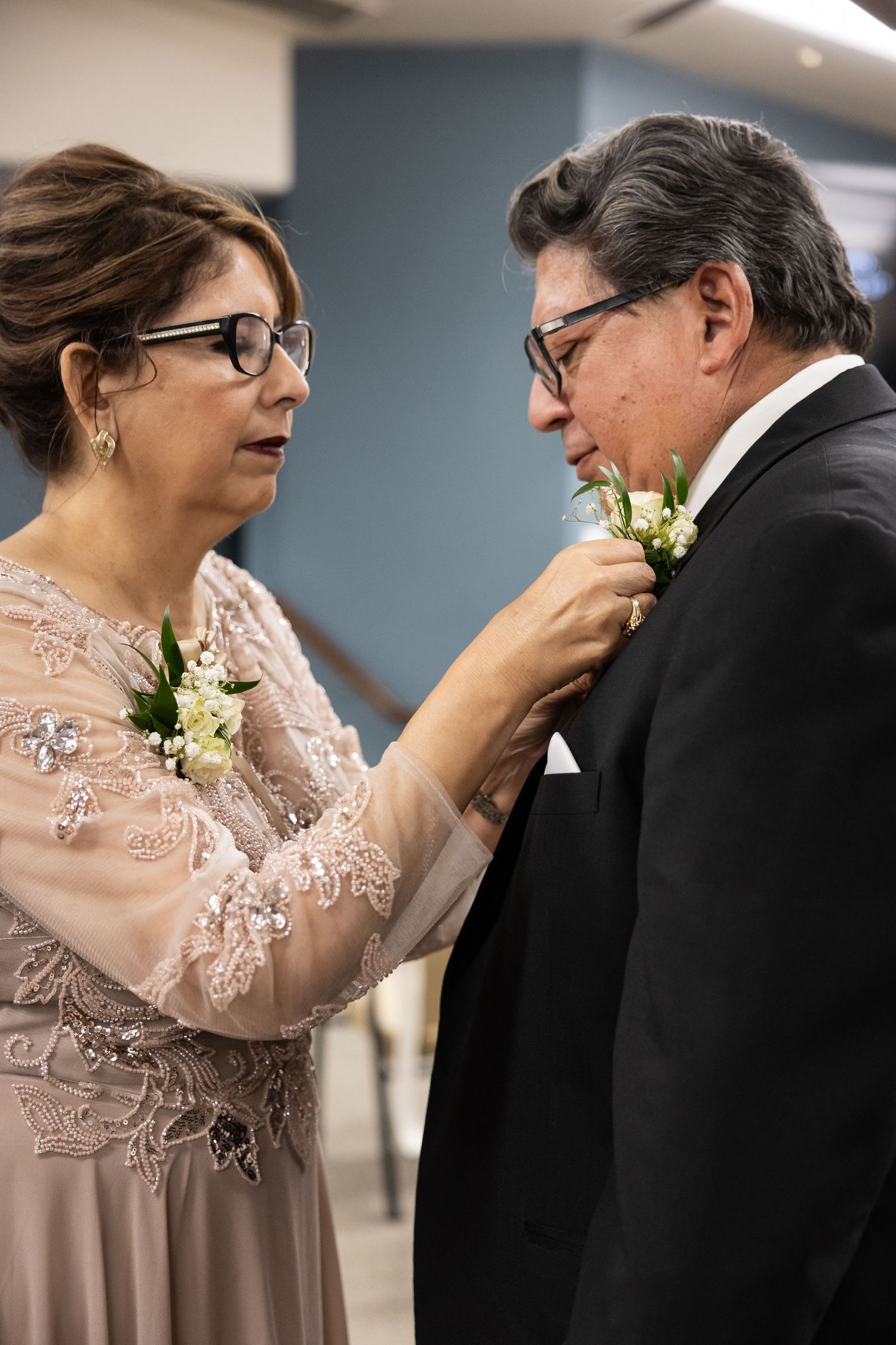 Tender interaction between two people wearing formal attire at an indoor event.