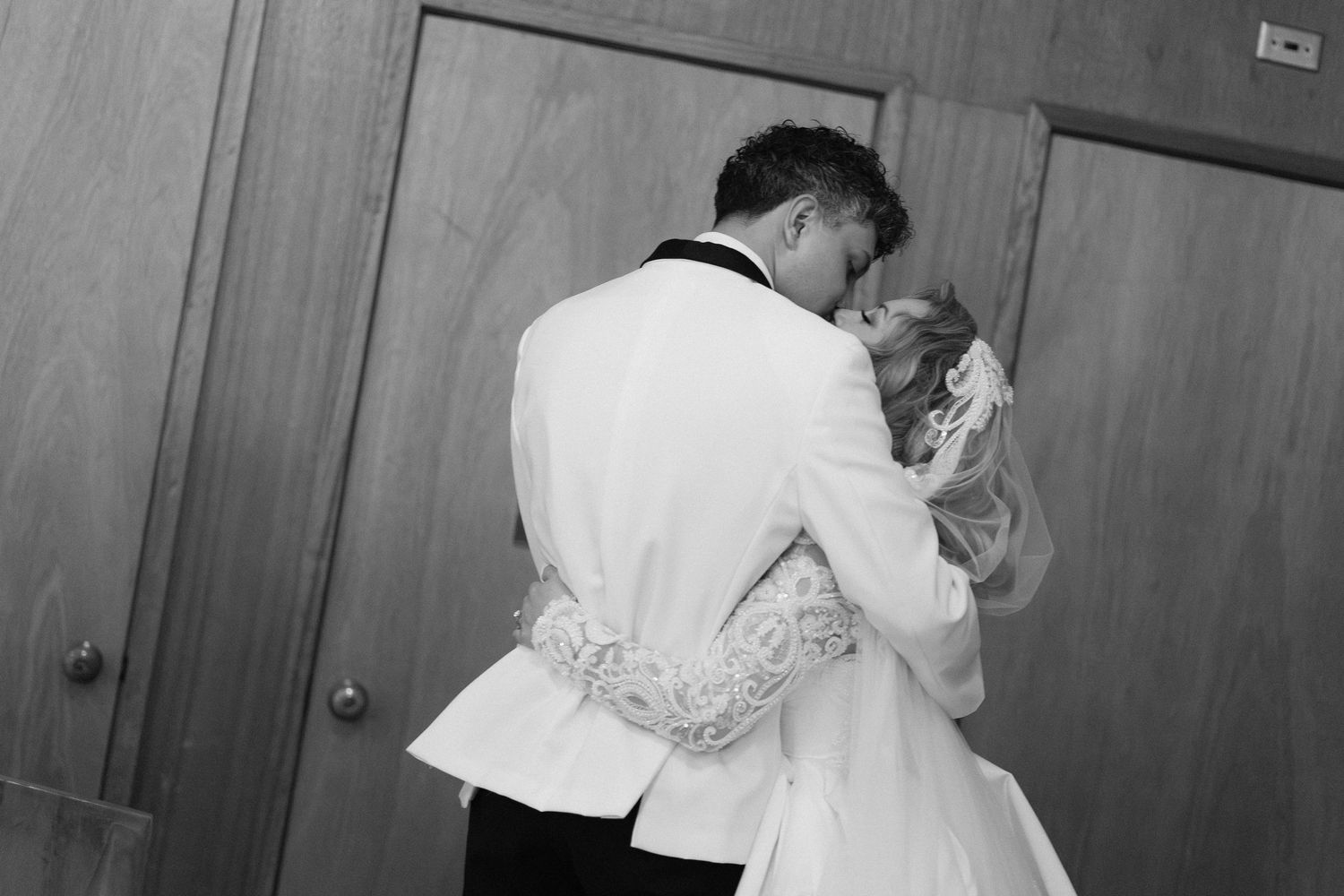Black and white photo of newlyweds sharing intimate moment during wedding celebration.