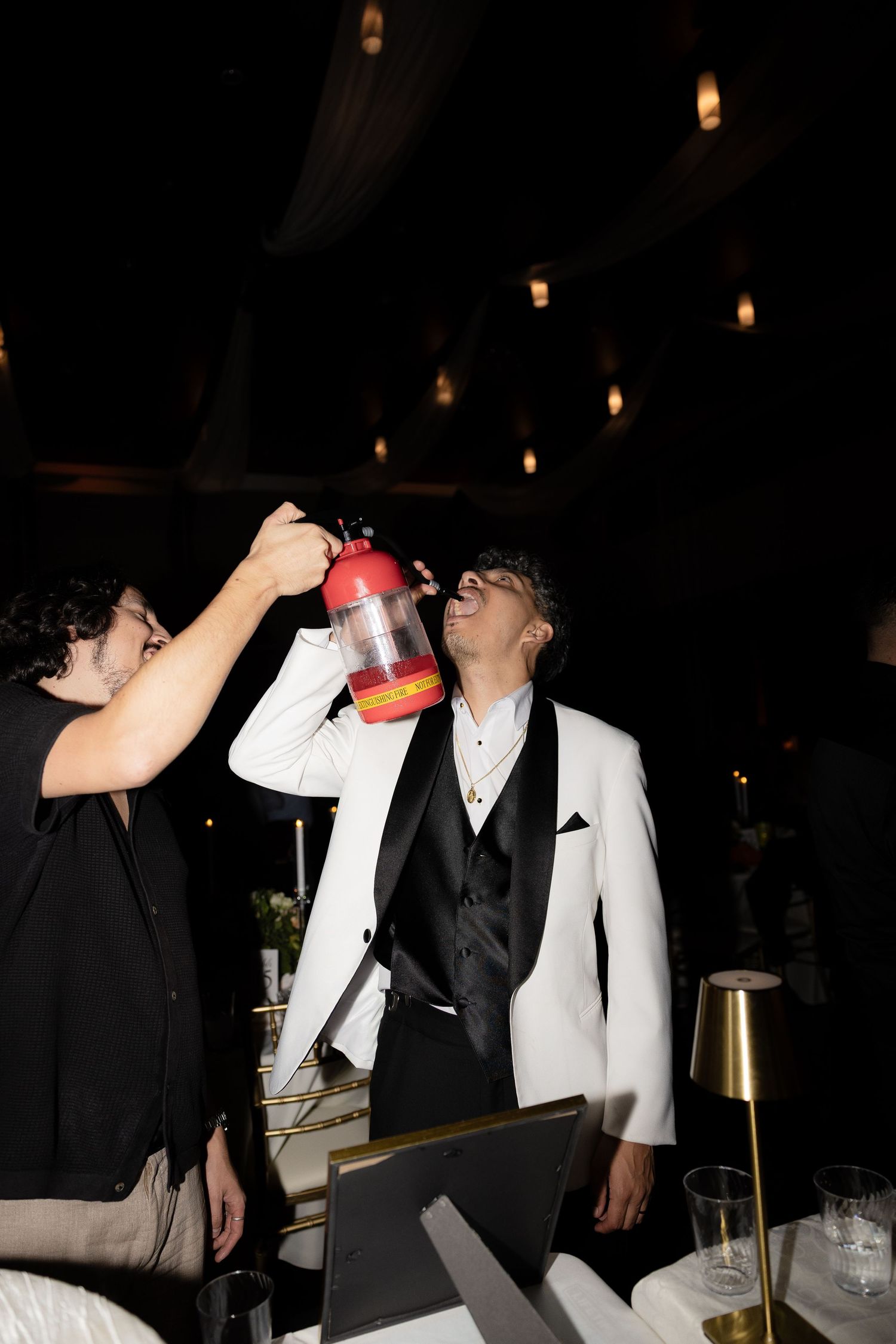 Wedding party taking shots together at a reception with dark ambient lighting.