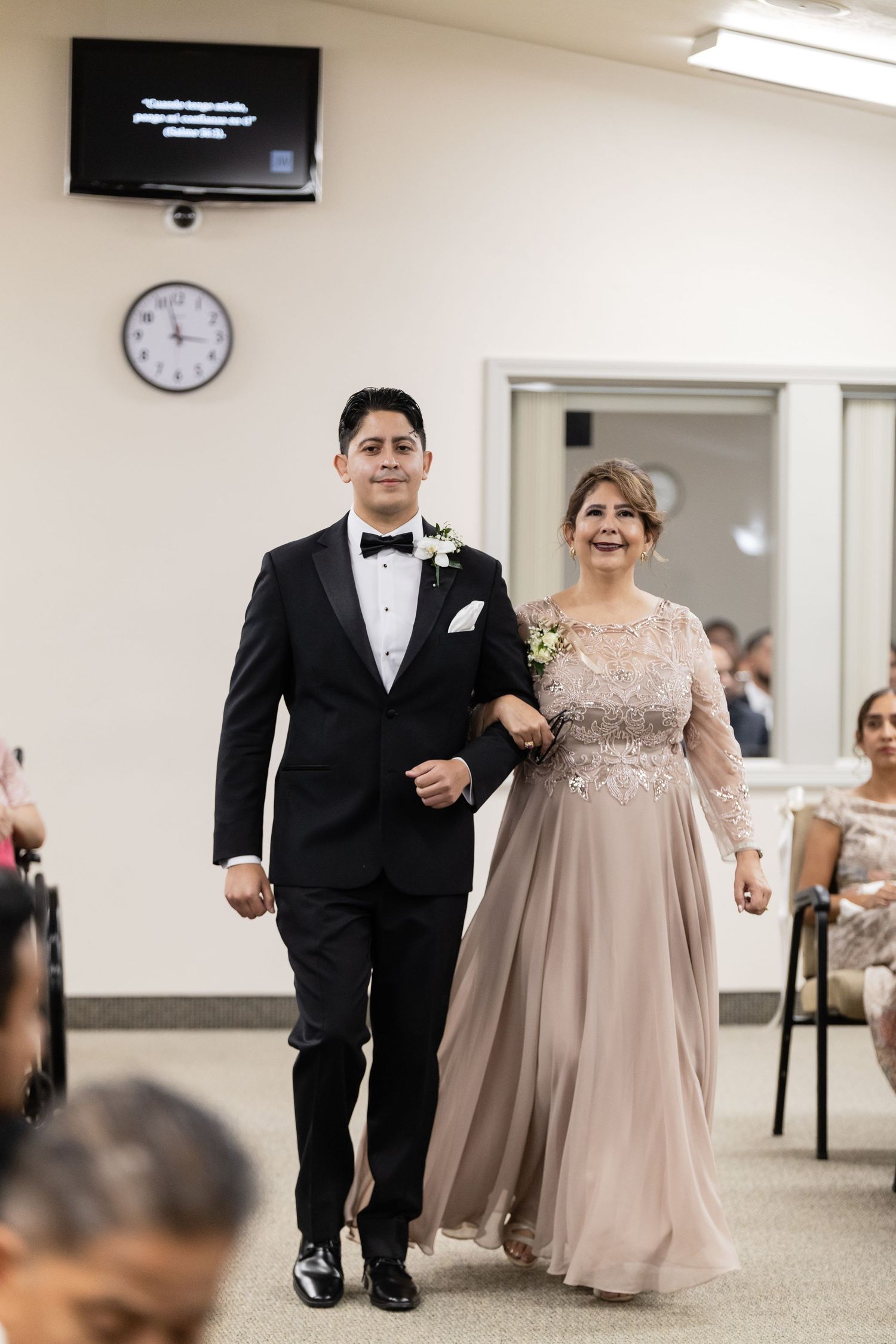 A couple in formal wear walking together at an indoor event.