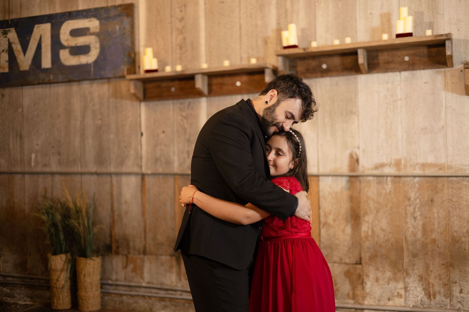 Couple embracing during dance in rustic venue with wooden walls and warm lighting.