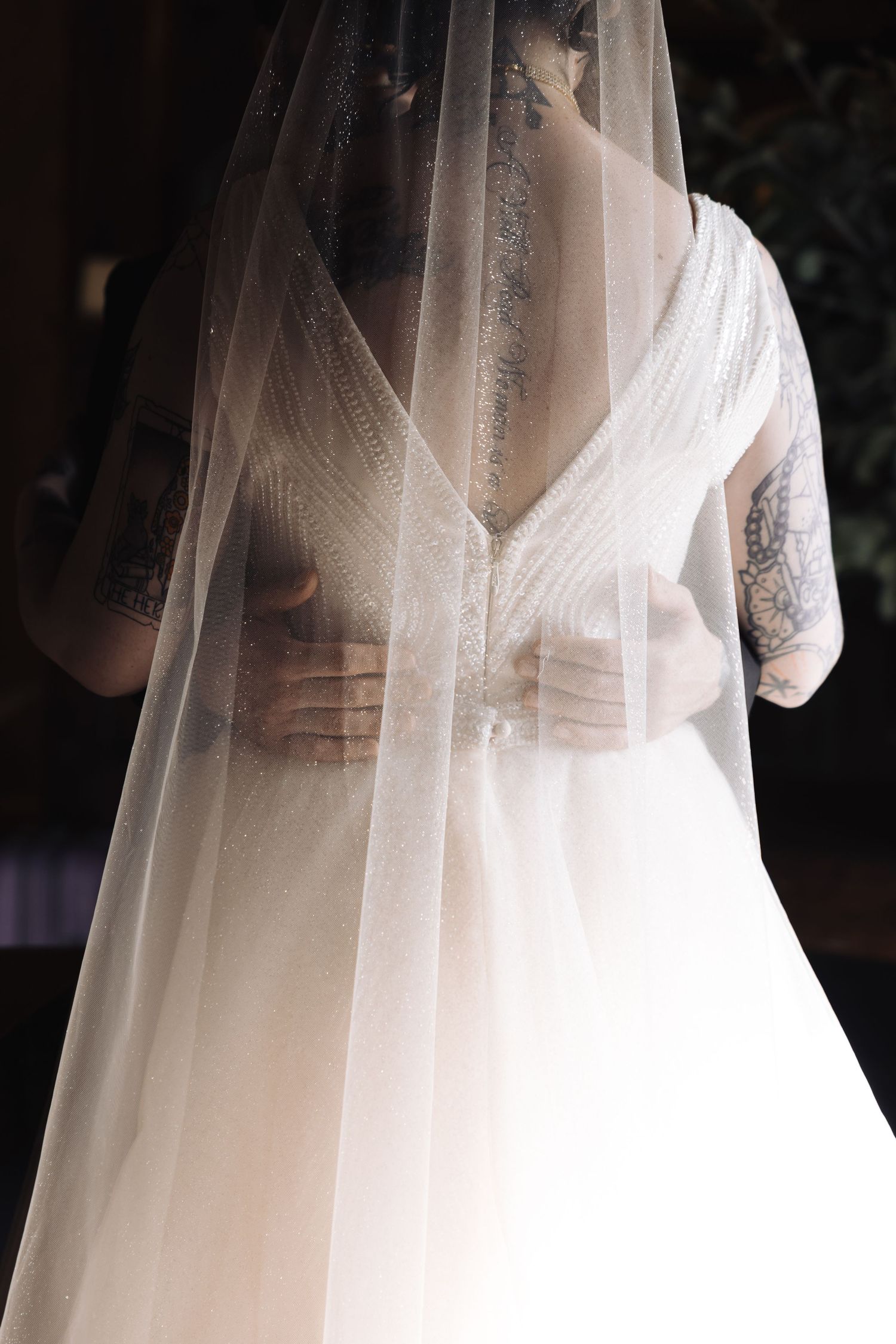 Close-up of a wedding dress bodice with intricate details through a sheer veil.
