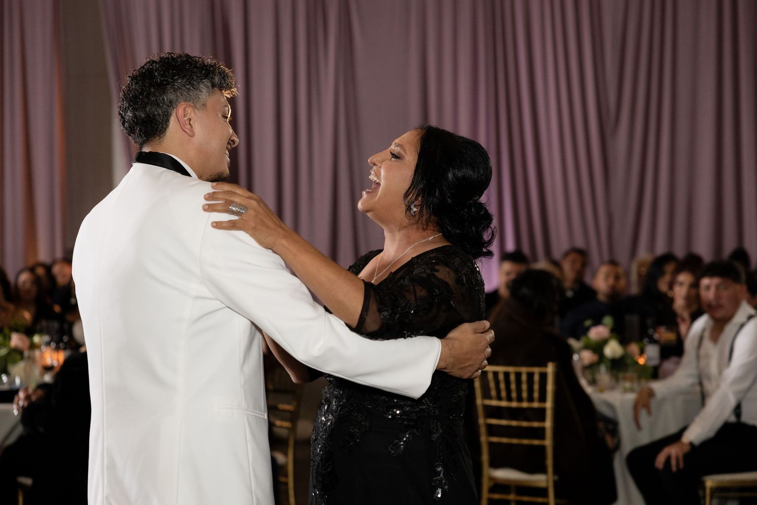 Couples dancing together at an elegant wedding reception with purple mood lighting.