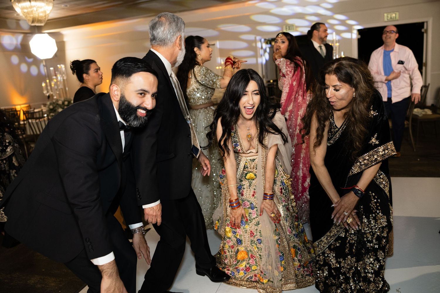 Guests in formal attire dancing and celebrating at an evening party.