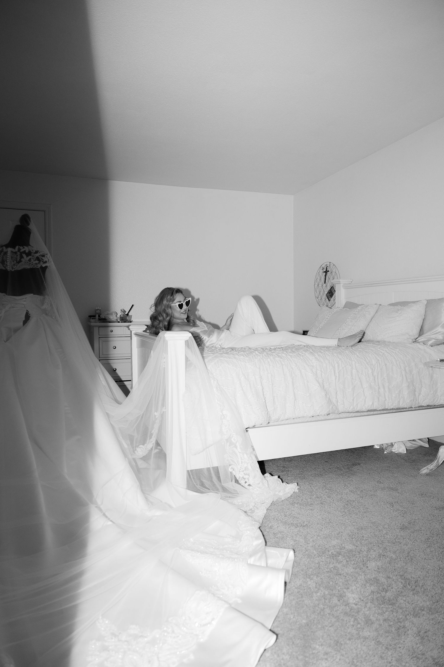 Black and white photograph of a bedroom with wedding dress display.