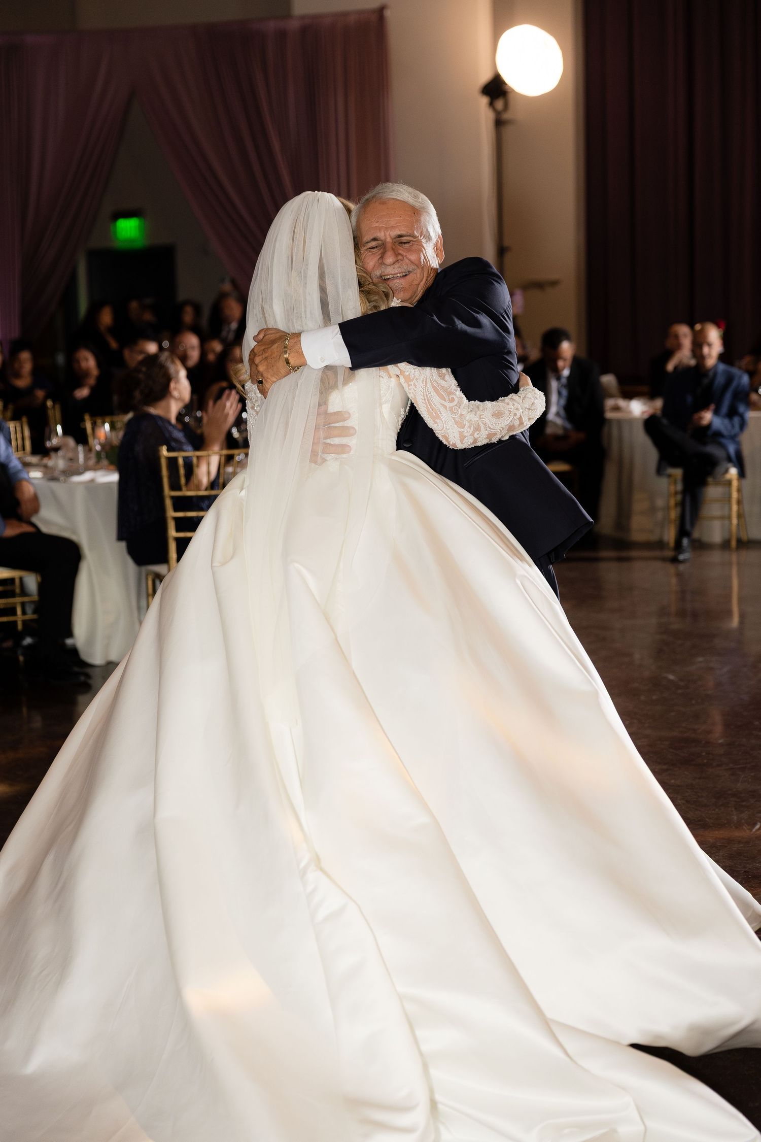 Bride in flowing white ballgown twirls gracefully during a romantic wedding dance.