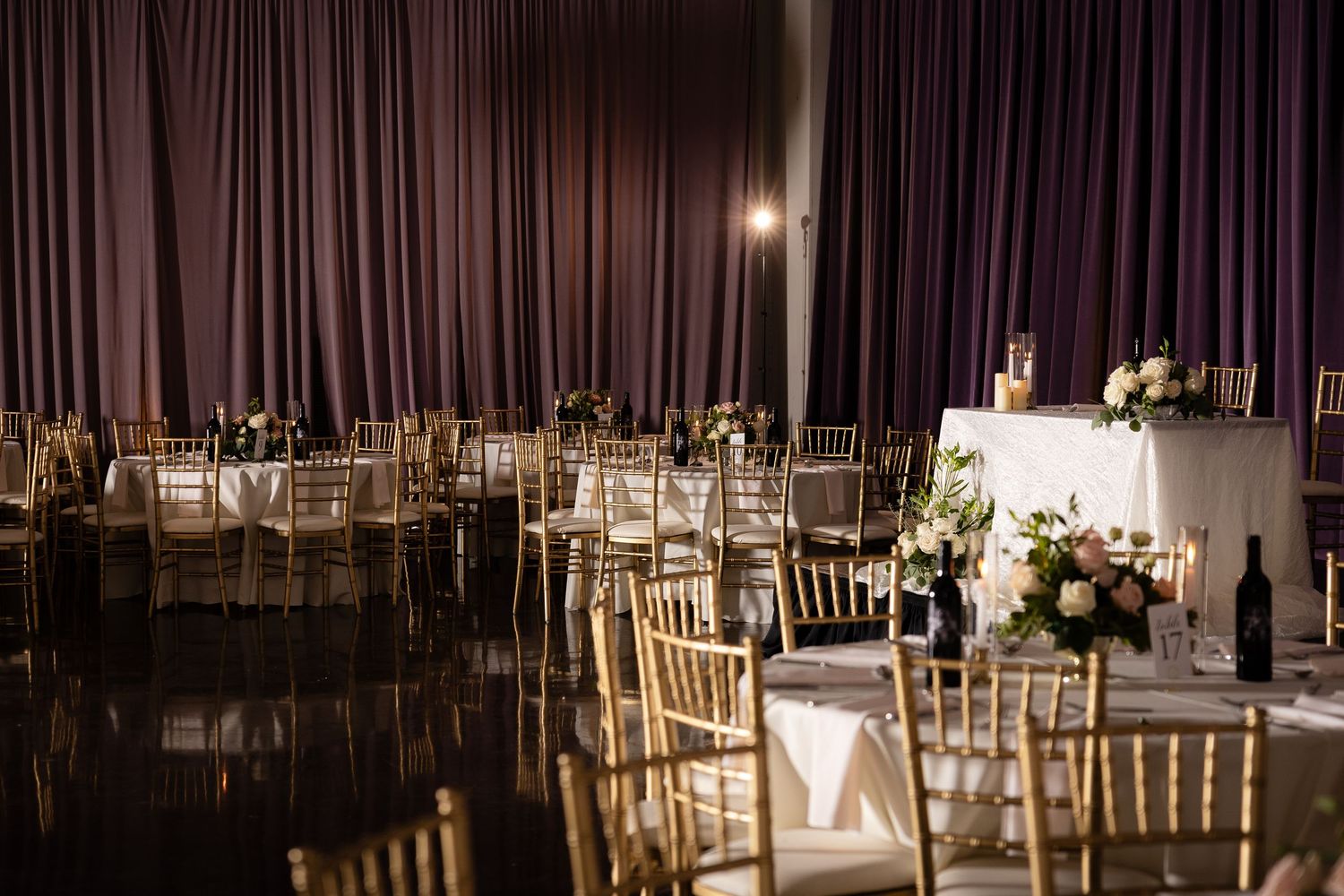 An elegant reception hall set with gold chairs and purple draping.