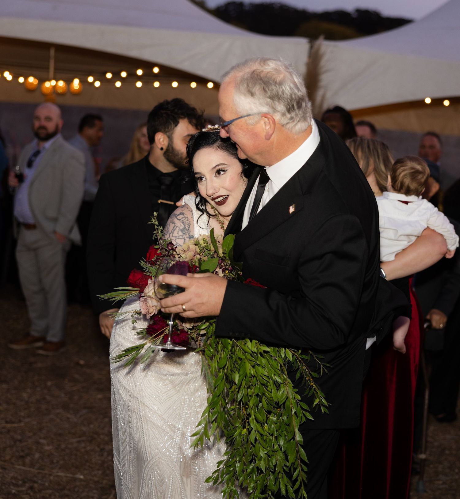 Wedding reception under tent with string lights and floral decorations.