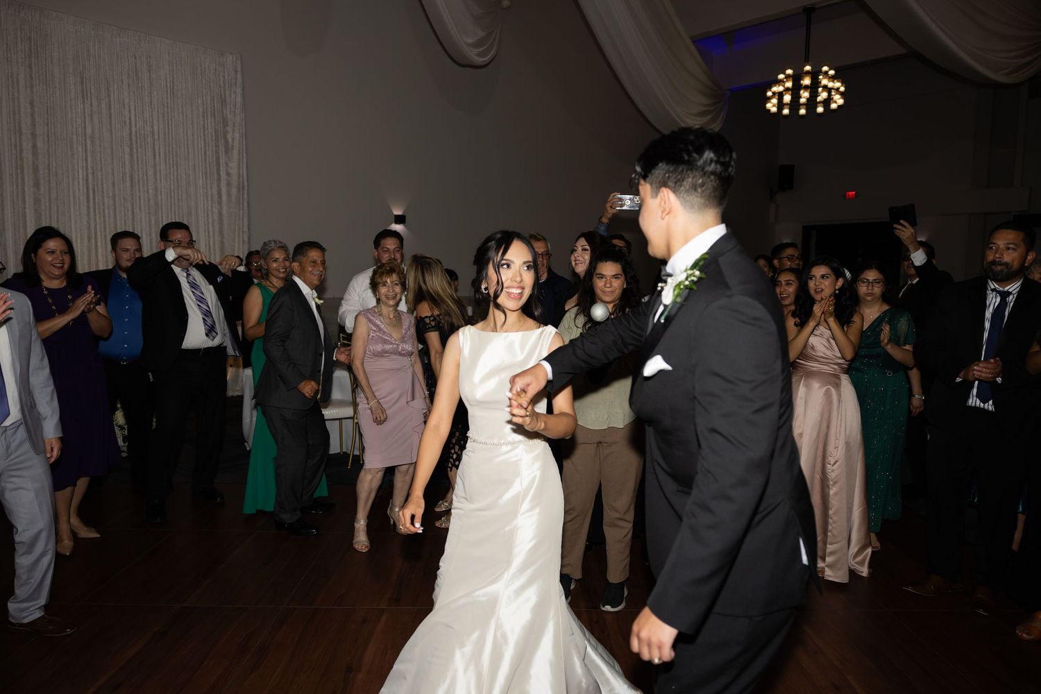 Wedding celebration with guests dancing under ambient lighting at indoor venue.