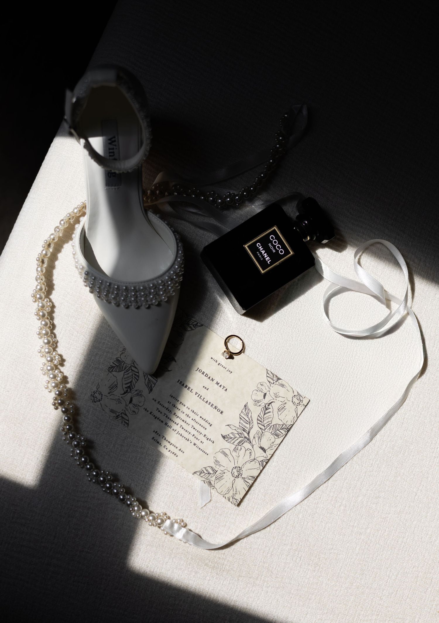 Wedding accessories and invitation suite arranged artistically with dramatic lighting.