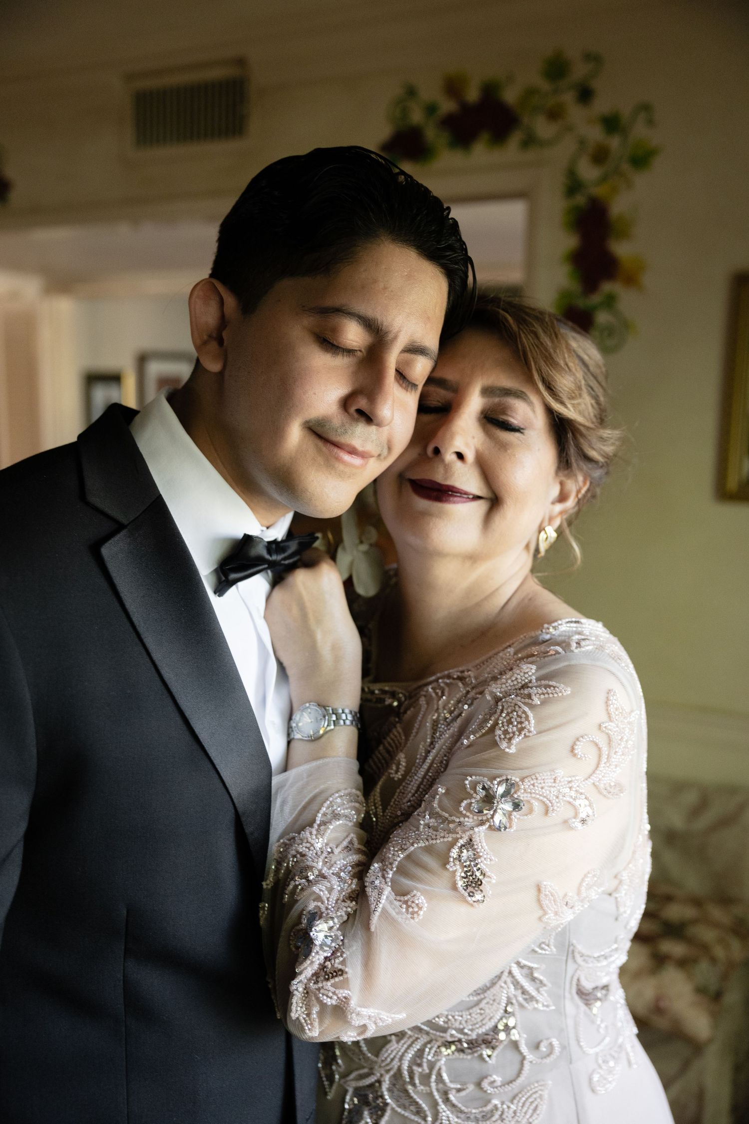 Intimate wedding portrait showing a couple in formal attire embracing in soft lighting.