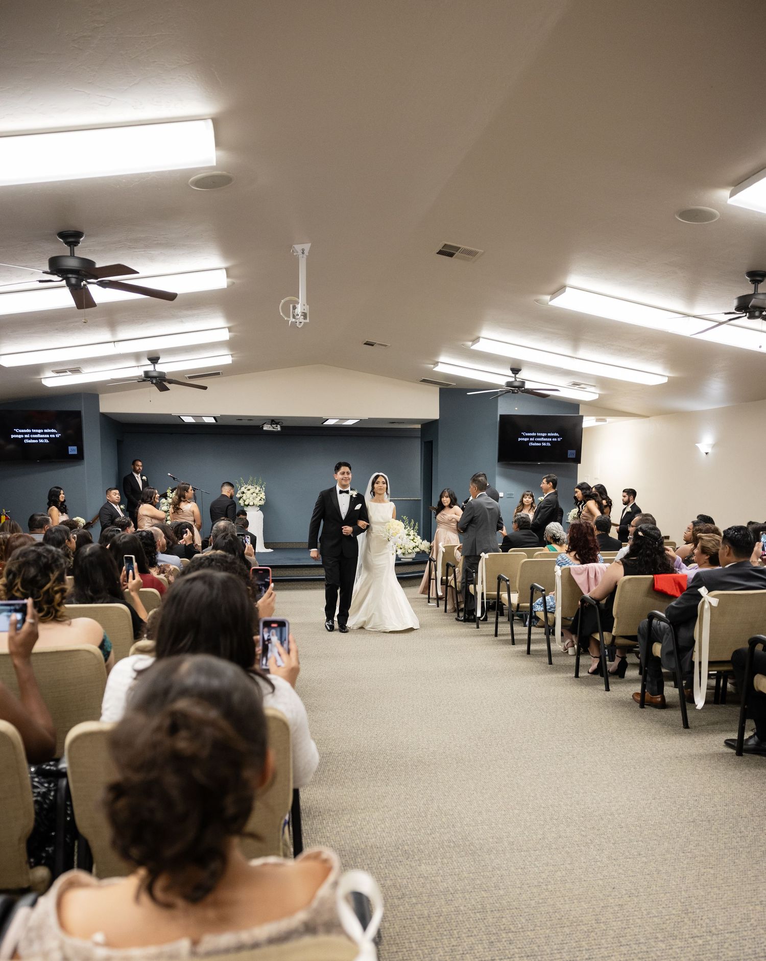 Wide view of a wedding ceremony space with rows of chairs and guests seated.