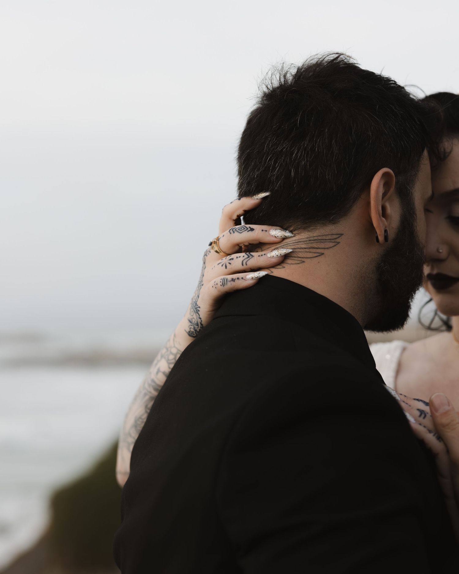 A couple shares an intimate moment during a romantic photoshoot with moody lighting and dark tones.