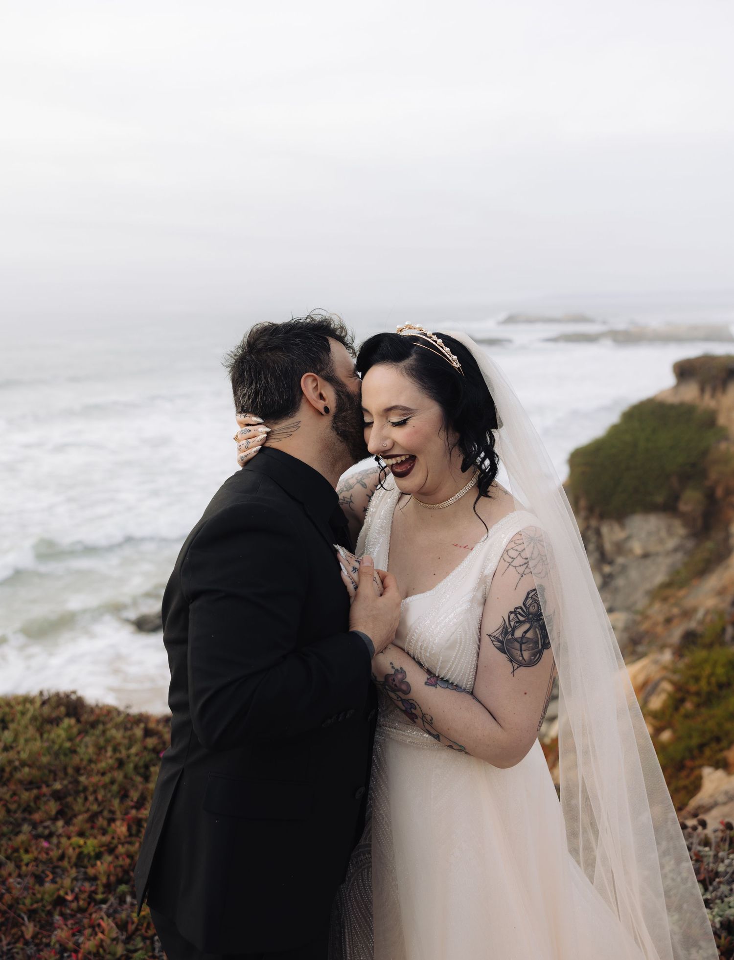 Candid wedding moment showing laughter and joy on a misty coastal cliff.
