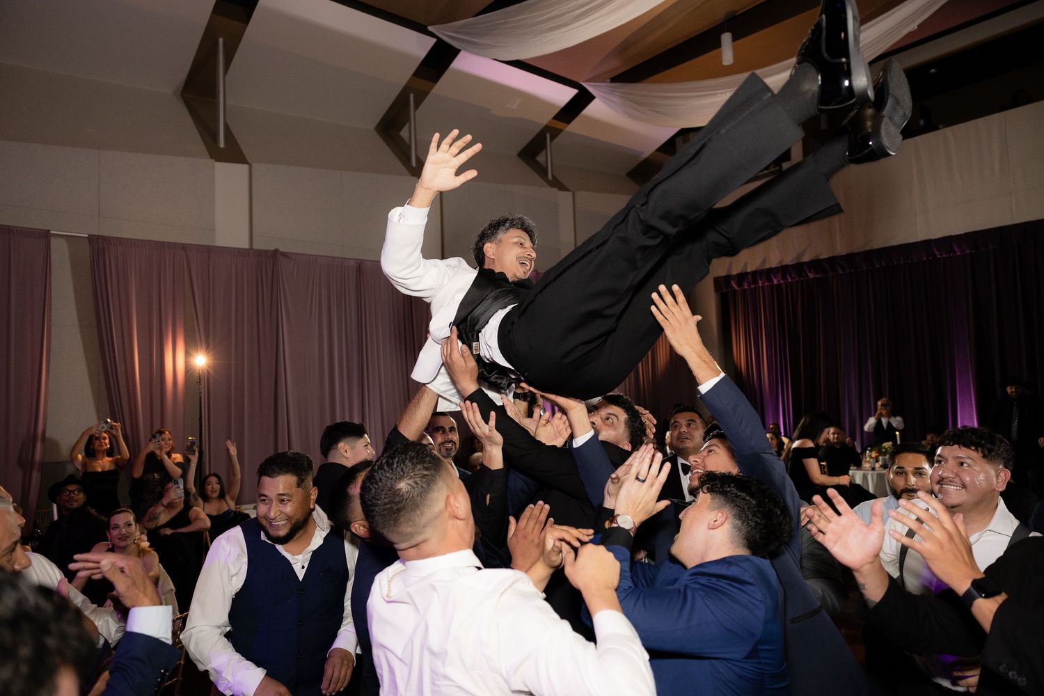 Guest gets lifted and crowd surfed across the dance floor at a wedding reception.