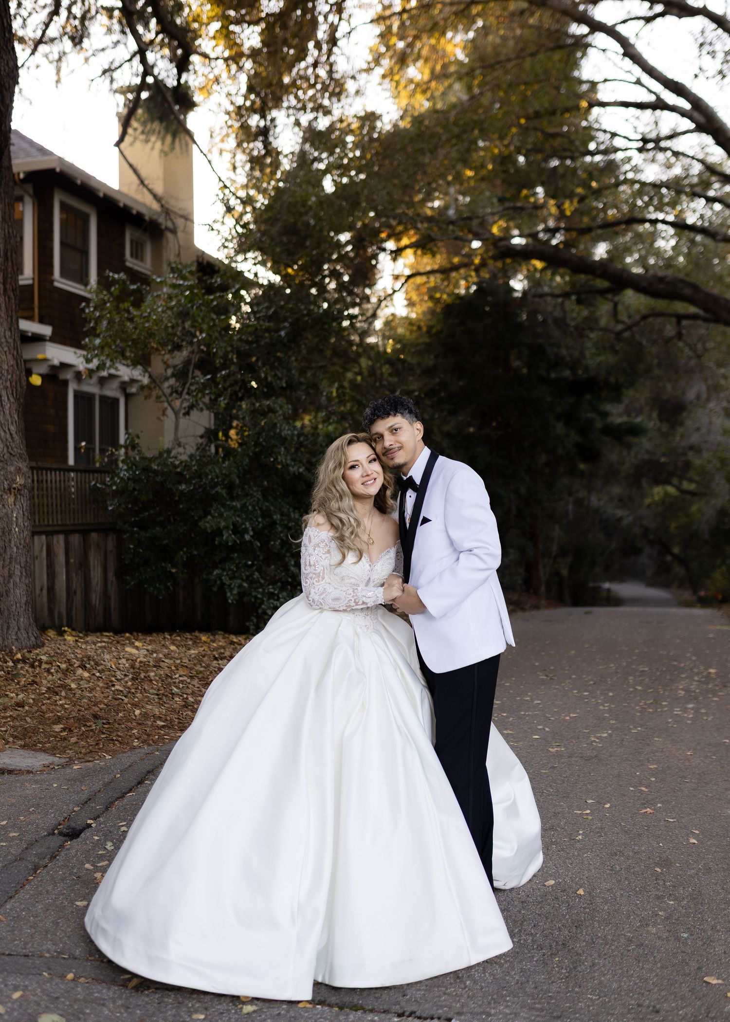 An intimate wedding portrait of a couple in formal attire against an autumn sunset background.