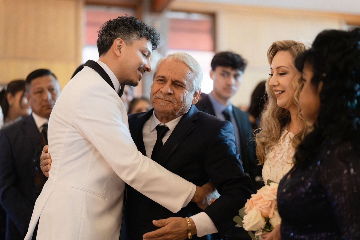Wedding celebration with guests hugging and interacting in church setting.