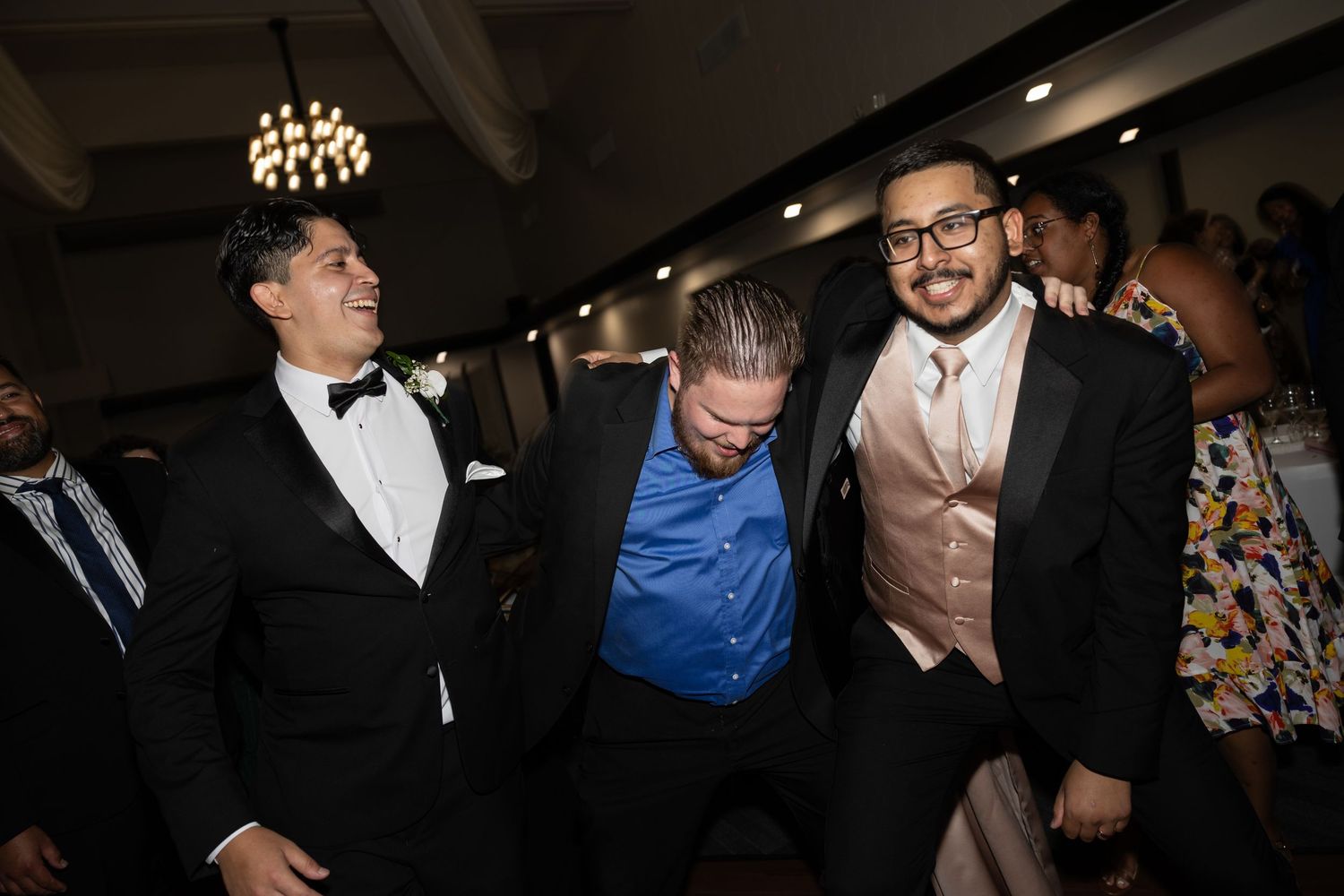Three guests sharing a candid moment of laughter at a formal event.