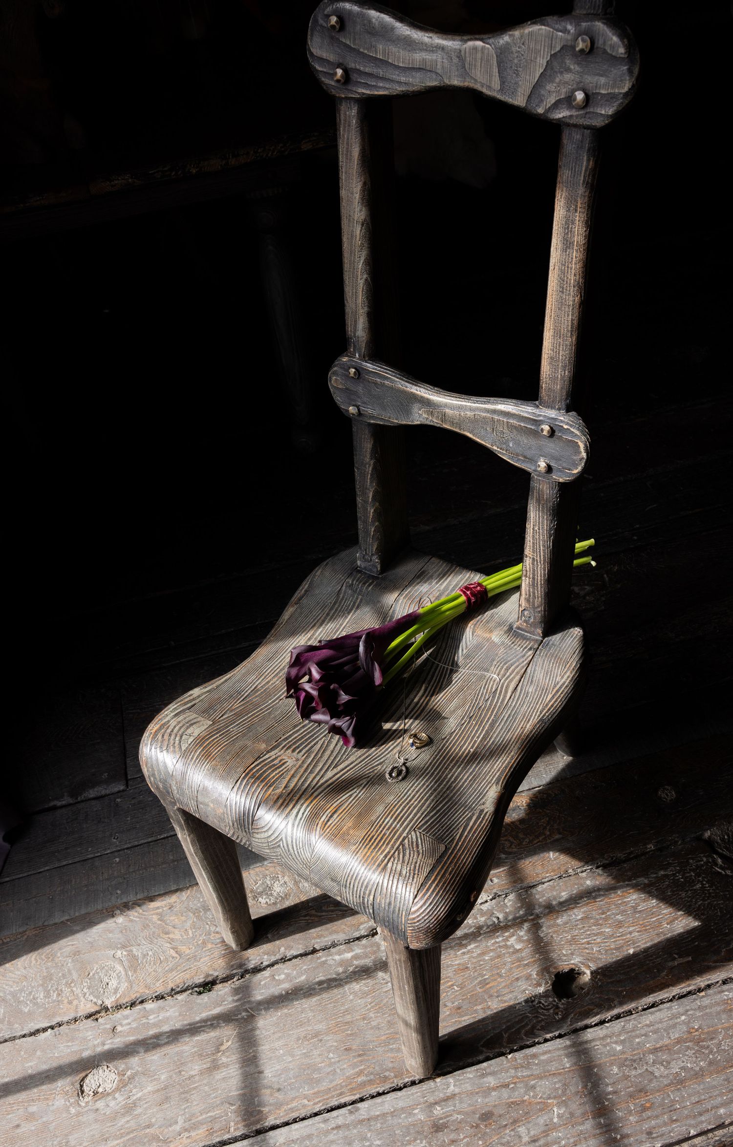 Antique wooden chair with purple flowers in moody lighting.