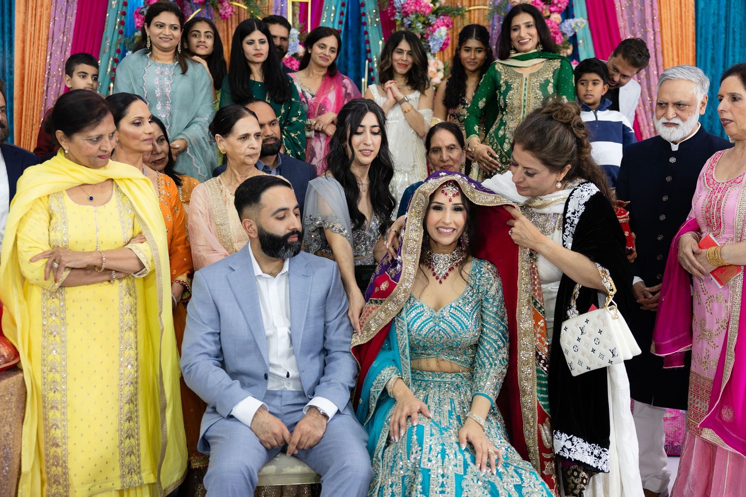 Wedding guests in bright traditional Indian outfits standing together at a celebratory event.