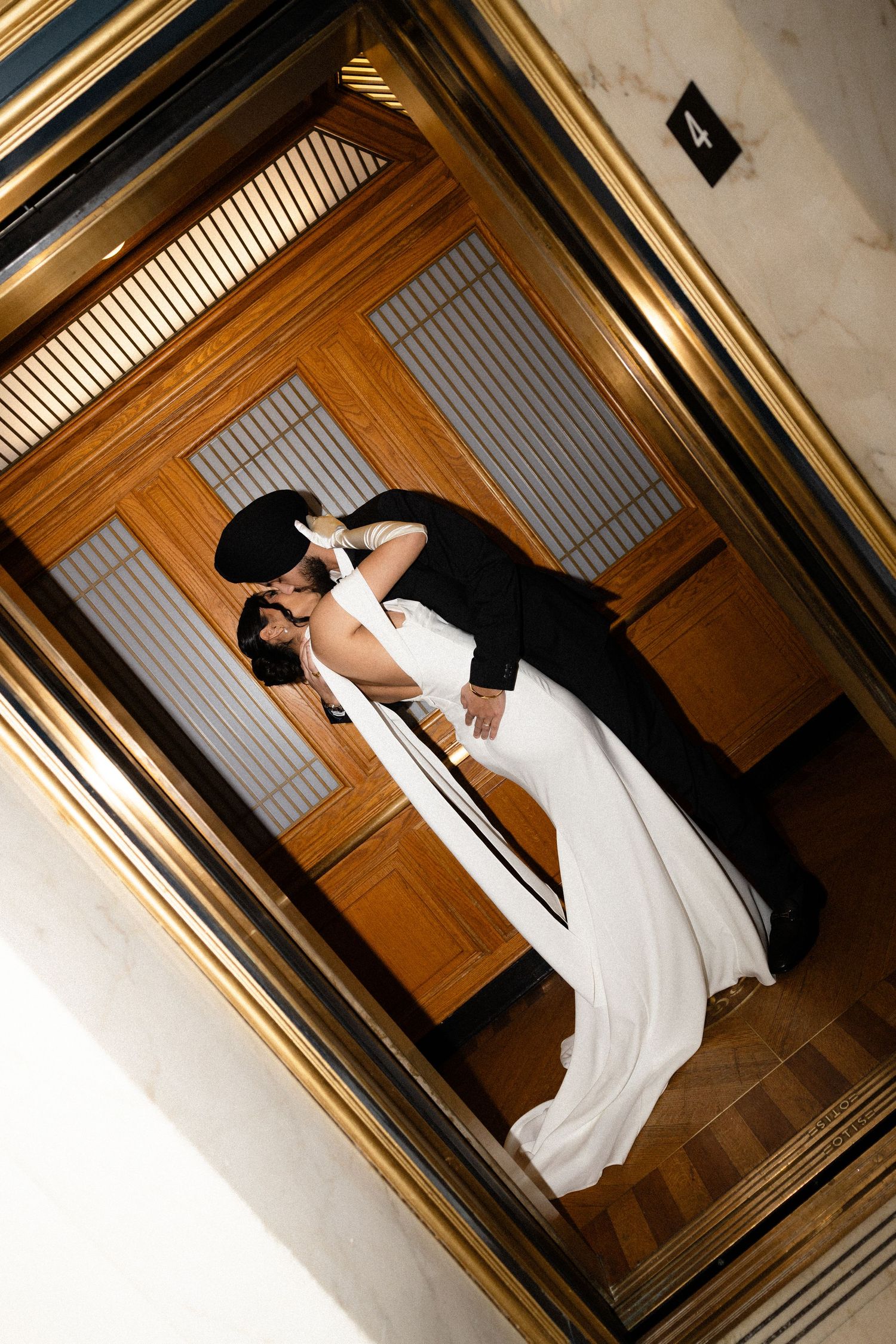 Romantic couple in formal attire sharing a tender moment in an elegant wood-paneled elevator.