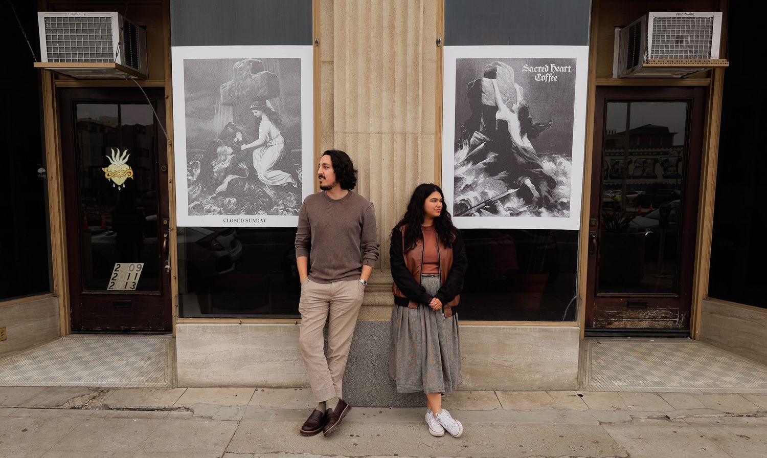 People walk past a series of framed photographs displayed on a wall in a gallery or exhibition space.