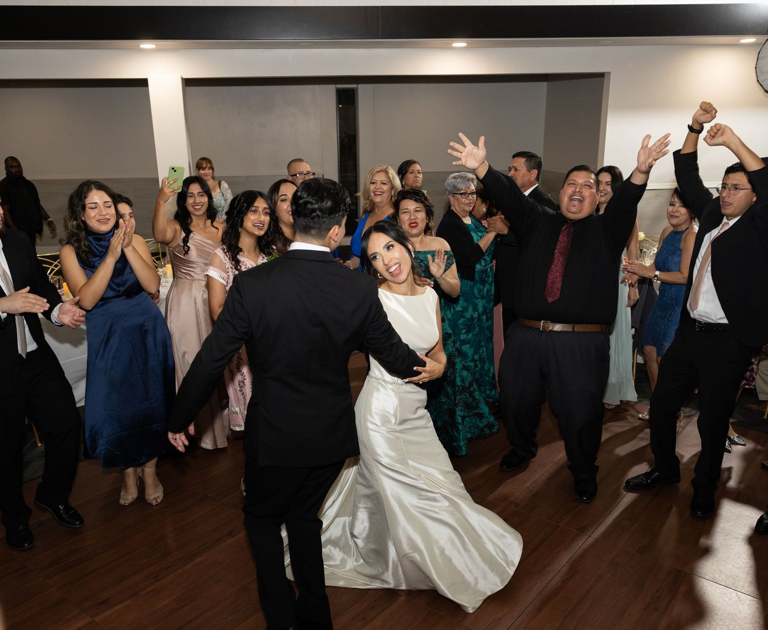 Wedding celebration on dance floor with guests in formal attire enjoying the festivities.