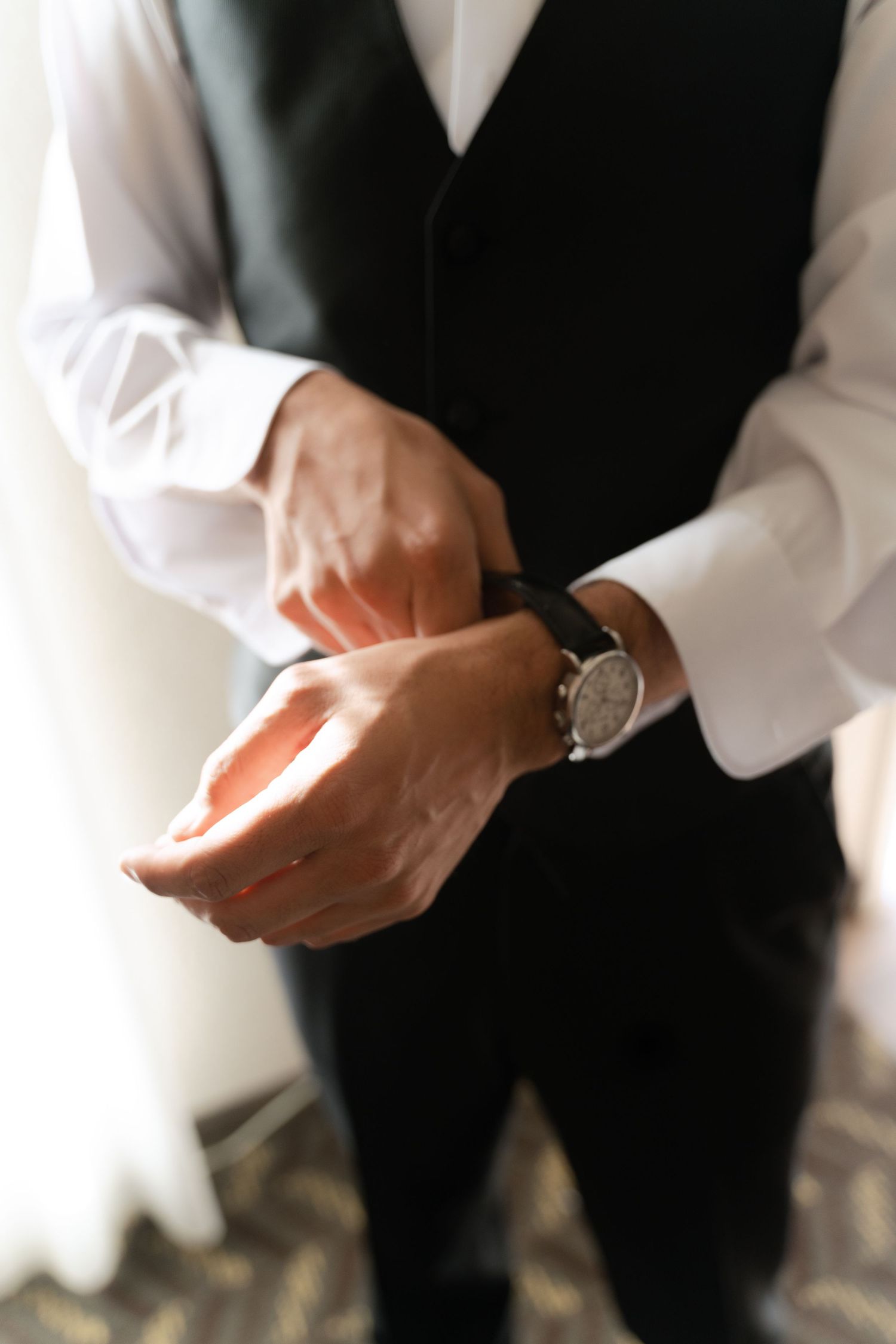 Close-up of hands adjusting formal attire against a black and white background.