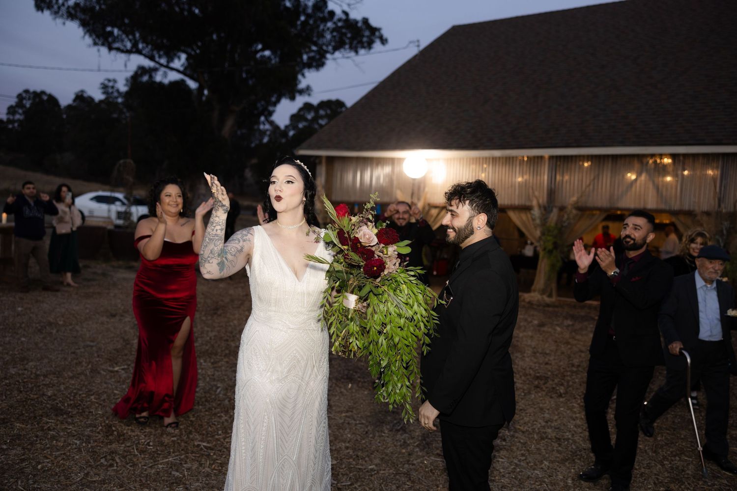 Wedding celebration outside rustic barn venue with evening lighting.