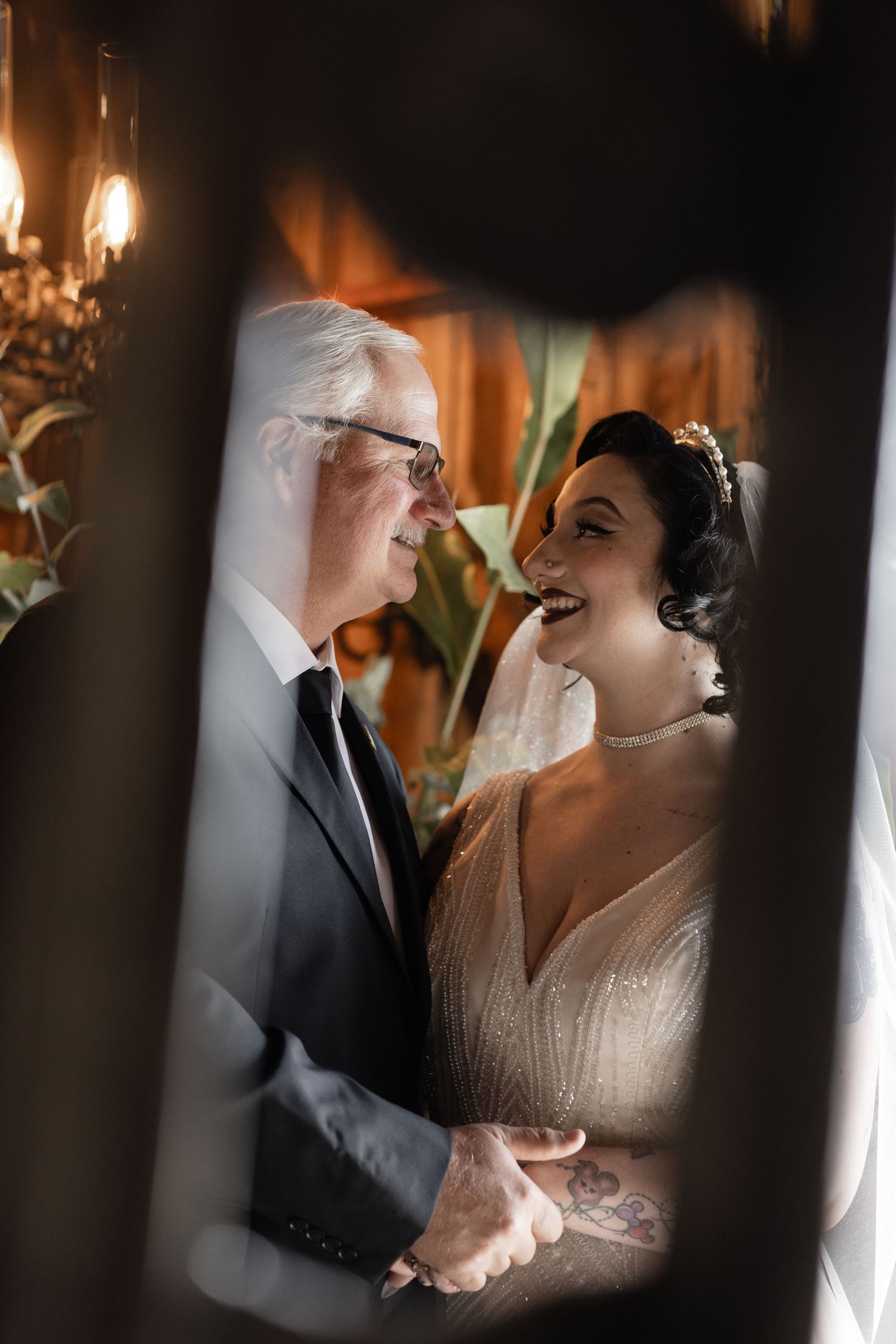 Artistic wedding photo showing tender moment through window panes with warm lighting.