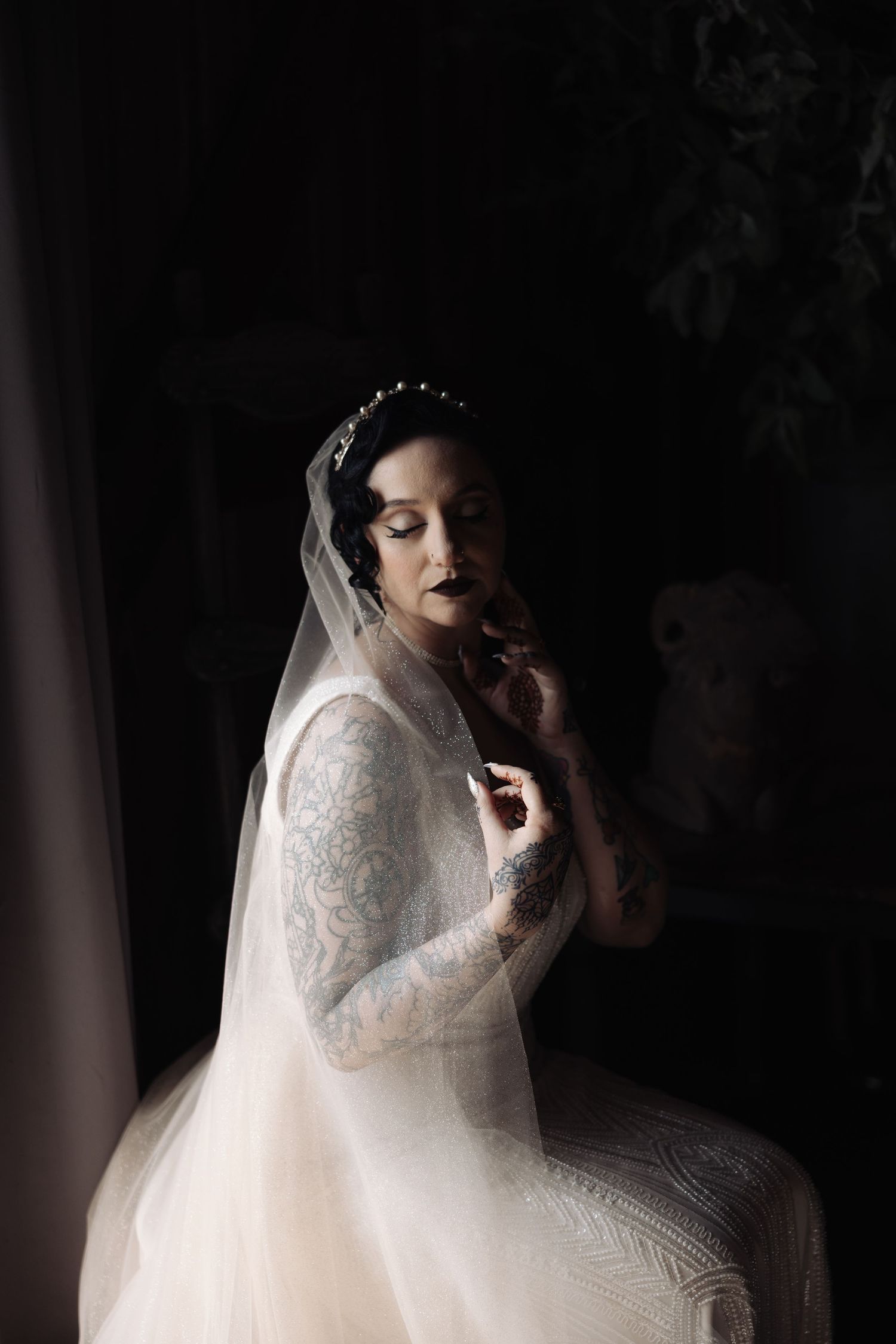 Artistic black and white bridal portrait with delicate lace details in low light.