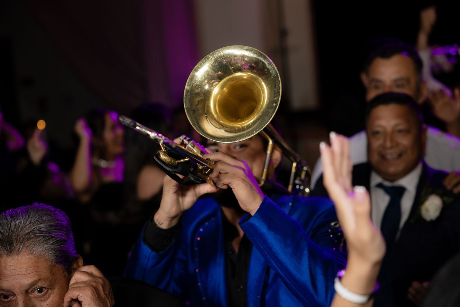 A trumpet player in bright blue performs at a wedding reception.