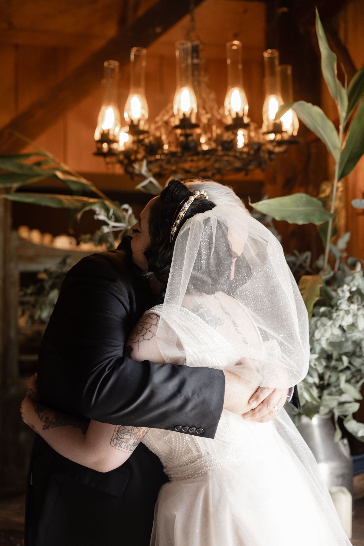 A romantic dance scene in a rustic barn with chandelier lighting and elegant white decor.
